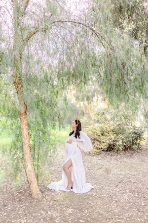 Dreamy maternity portrait under weeping willow tree branches.