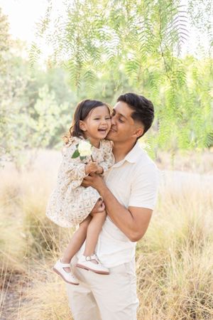 Playful father-daughter moments captured in a sunny outdoor setting.