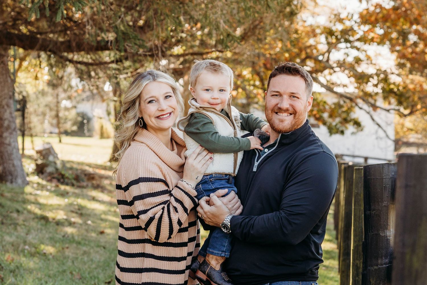 A happy family poses together outdoors on an autumn day.