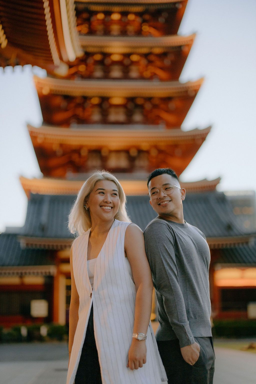 Couple posing in front of a traditional Japanese pagoda temple during golden hour.