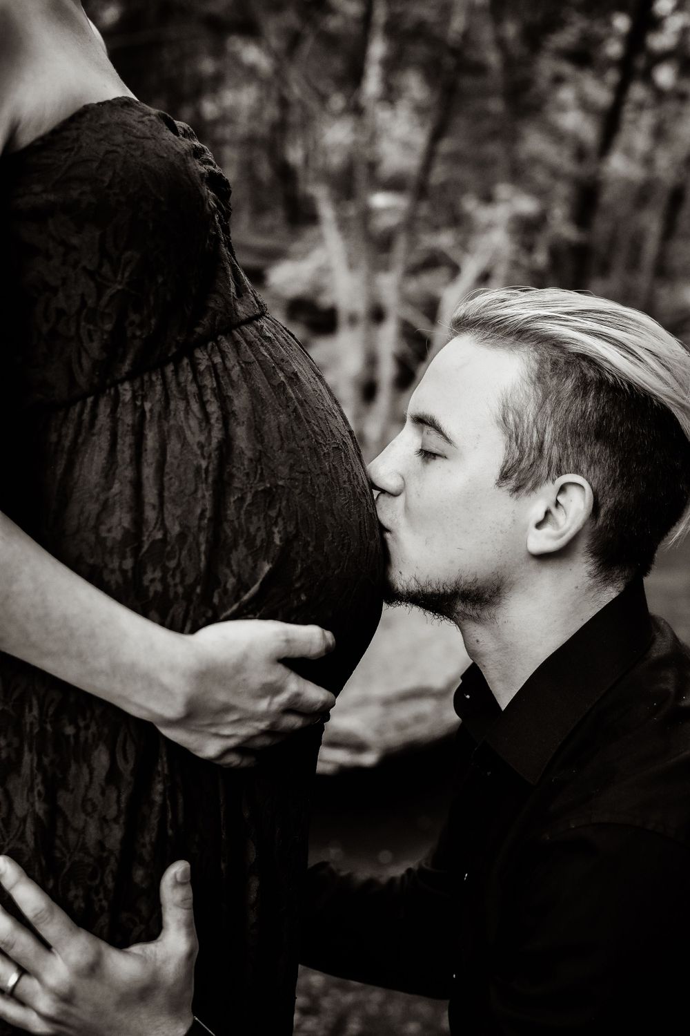 Husband kissing wife's pregnant belly during an outdoor Fort Worth Maternity session