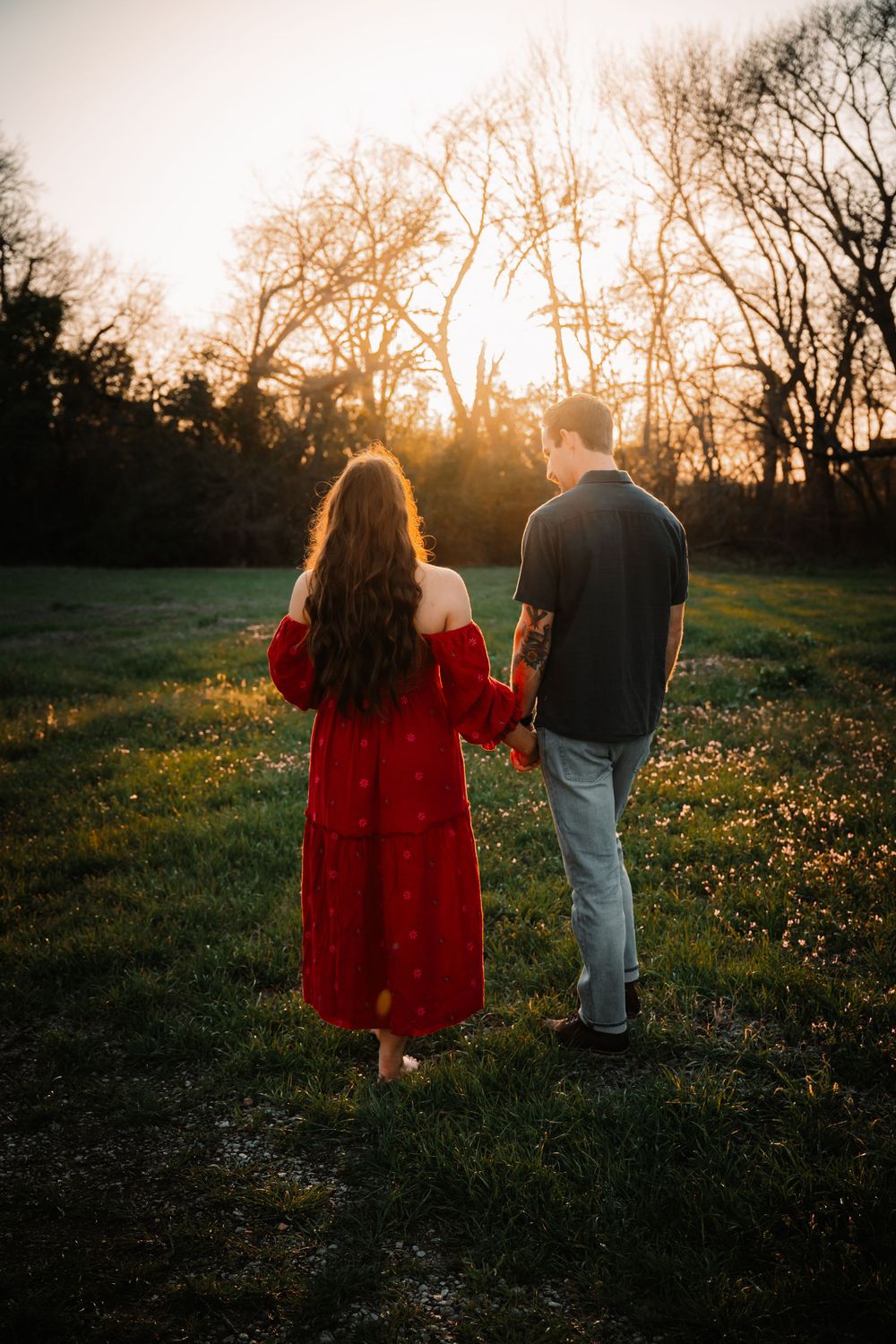 Expecting couple walking hand in hand at sunset during outdoor maternity session in Dallas–Fort Worth