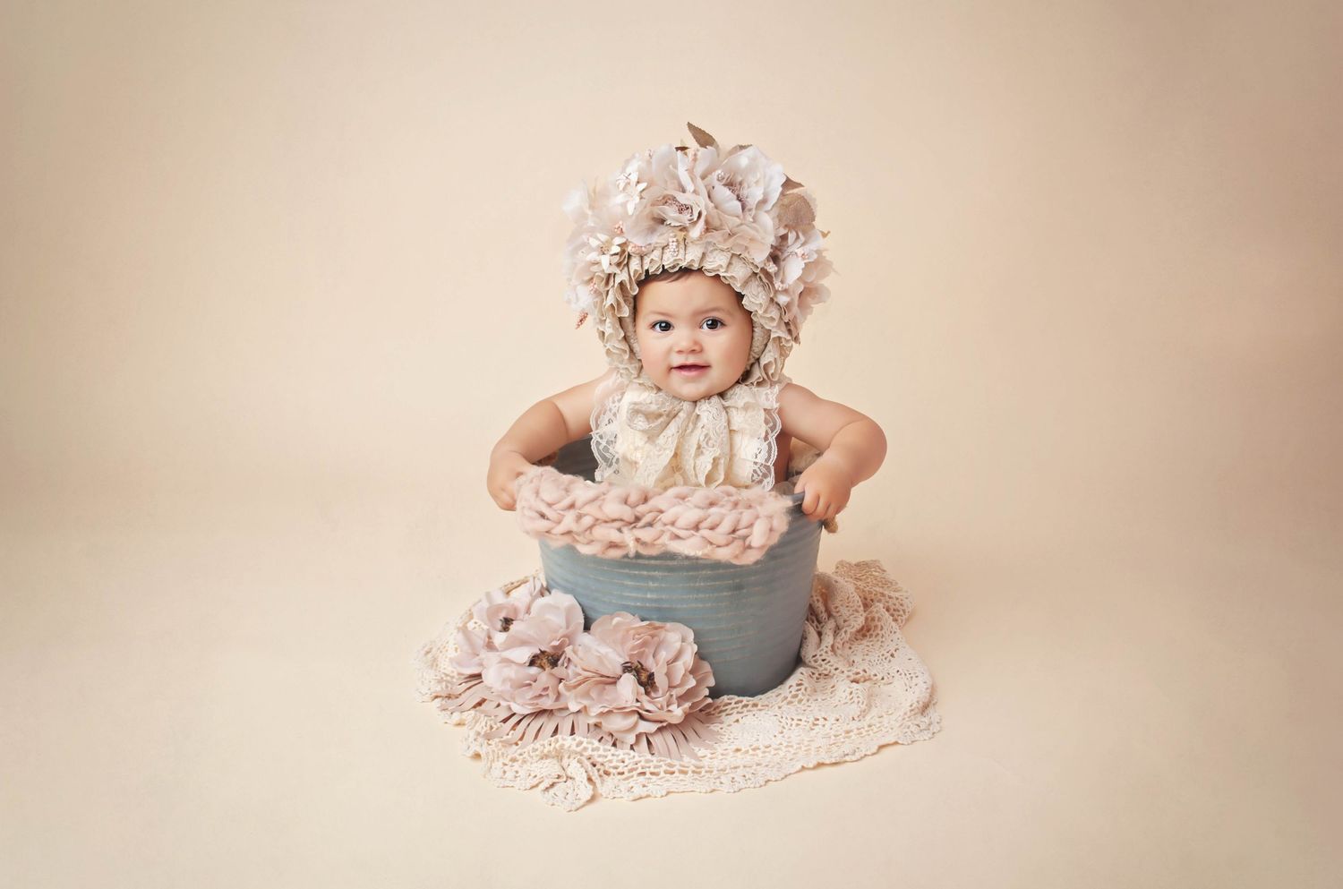 1 year little girl with floral bonnet on cream tan in bucket