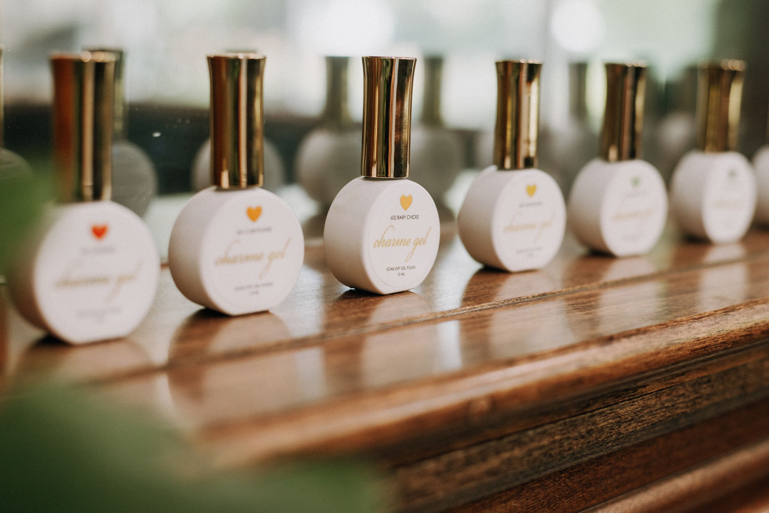 Row of white perfume bottles with gold caps displayed on wooden shelf.