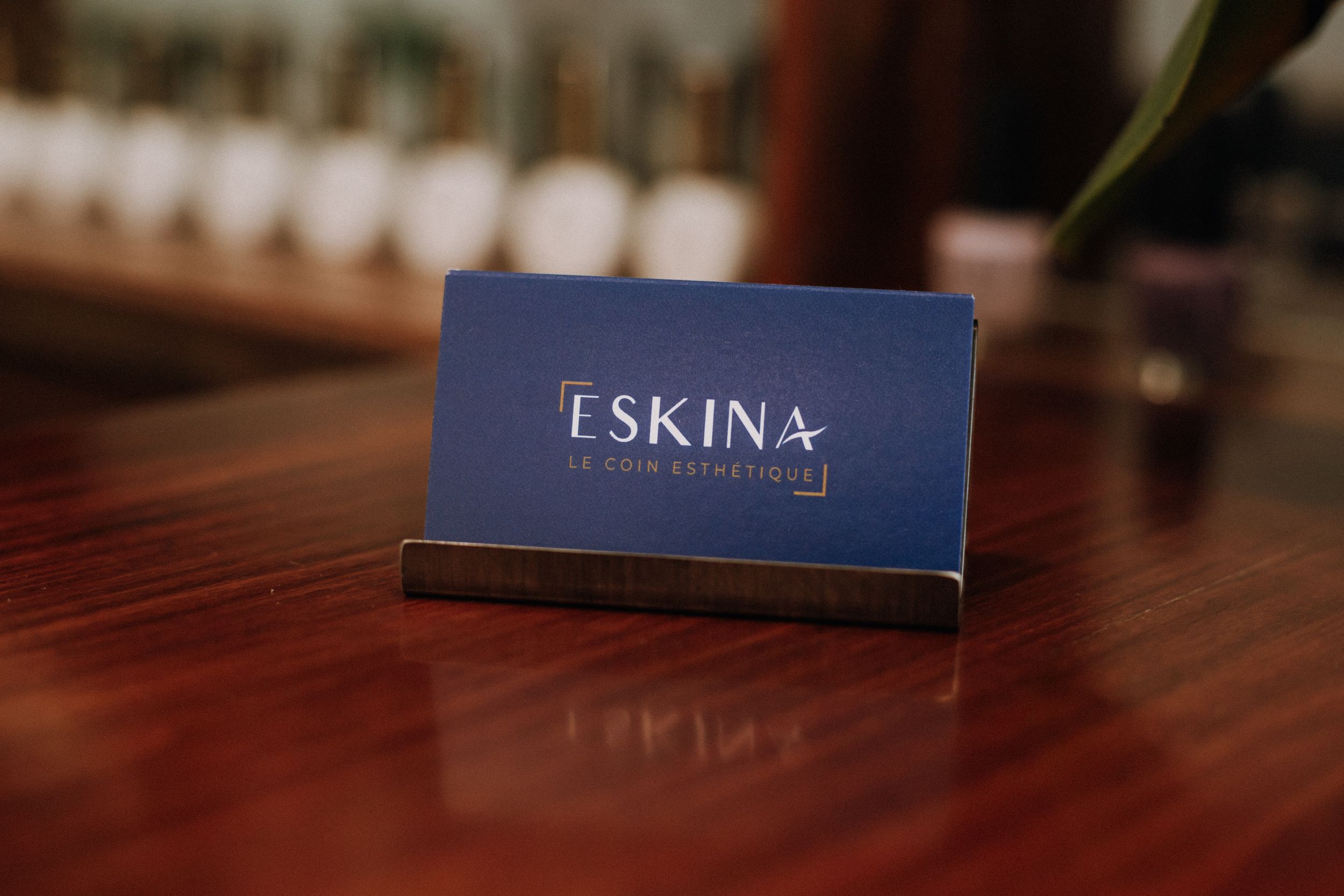 Close up of navy blue Eskina business card on wooden surface.