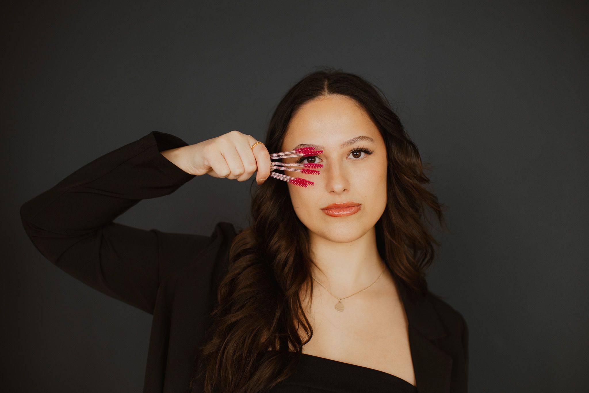 Studio portrait against dark background with makeup brush.