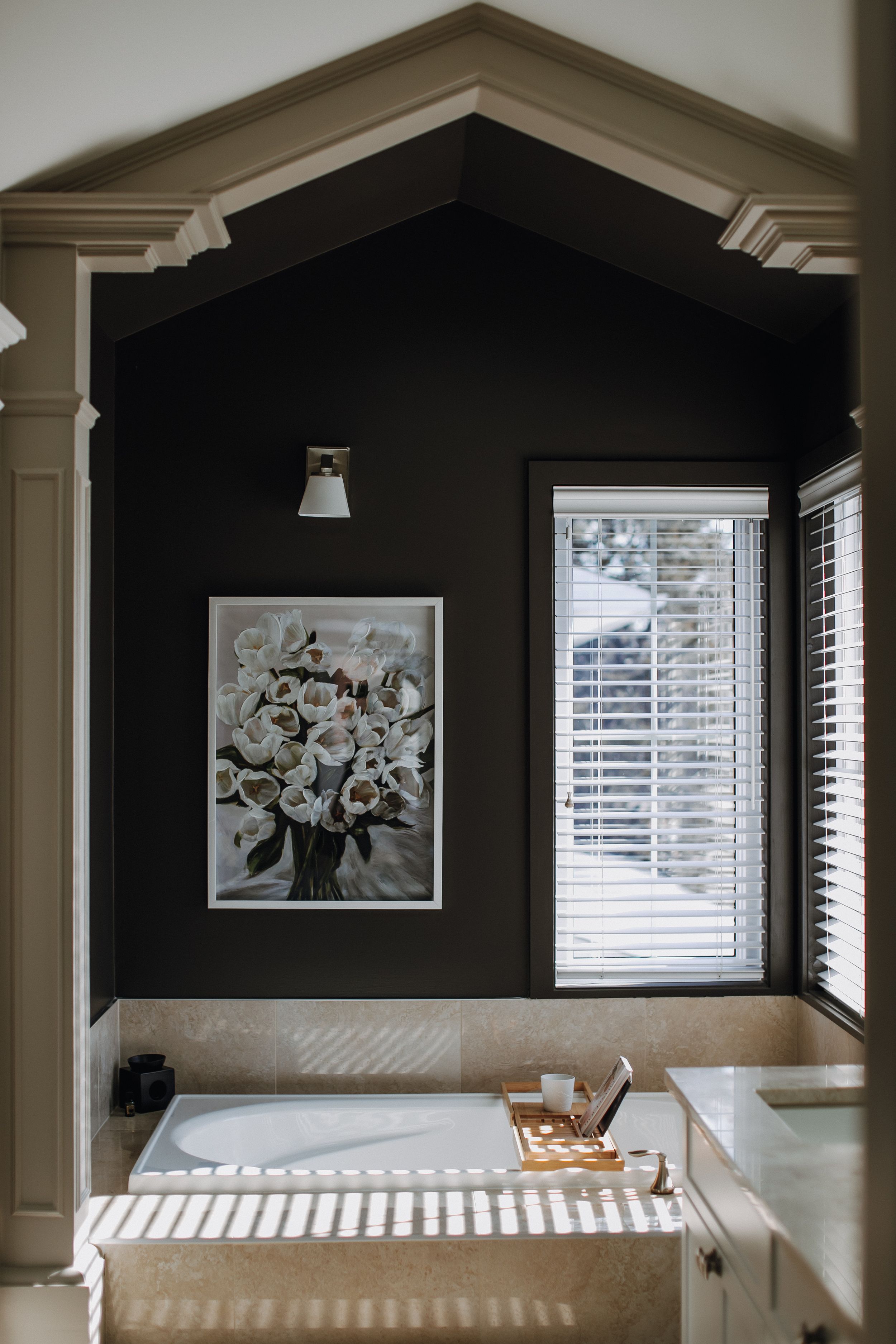 Modern bathroom features a dark accent wall with floral artwork and white trim details.