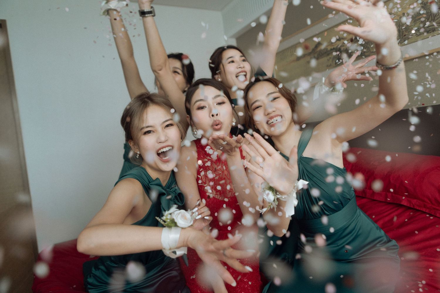 Bridesmaids in dresses celebrate joyfully with confetti at a wedding party.