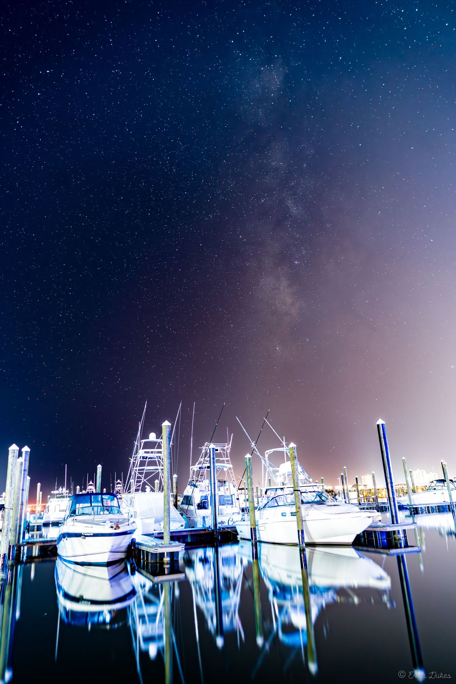 Milky way behind yachts and boat reflections on water