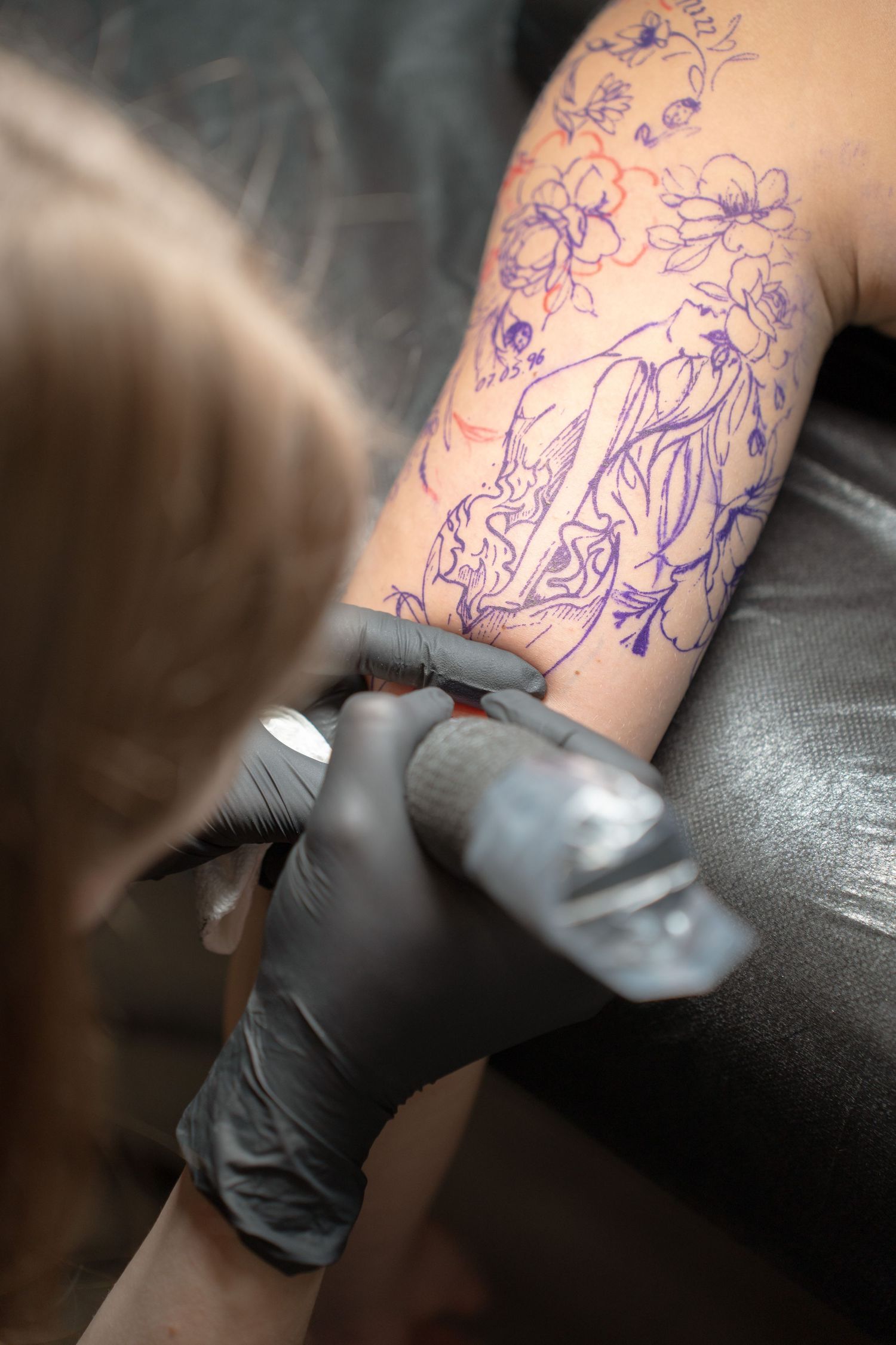 Detailed floral tattoo being applied with professional equipment.