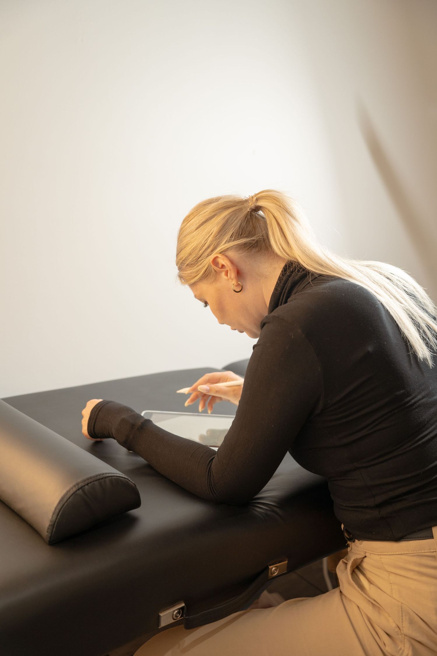 Someone in black attire examining notes on a massage table.