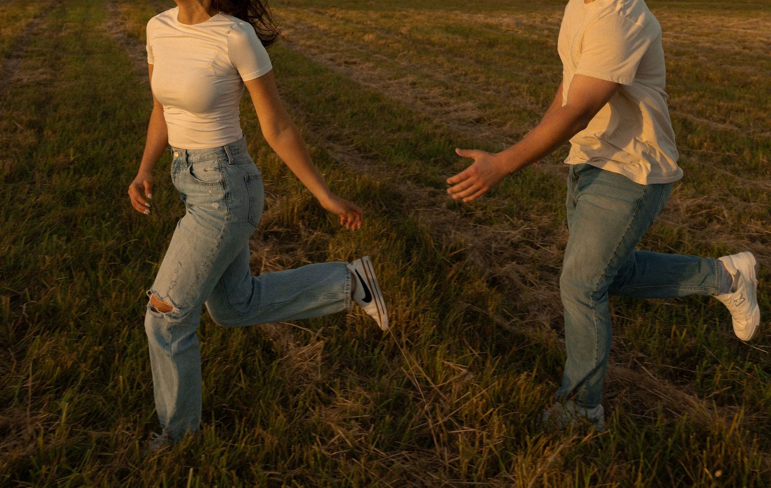 People in casual outfits walking through a golden field at sunset.