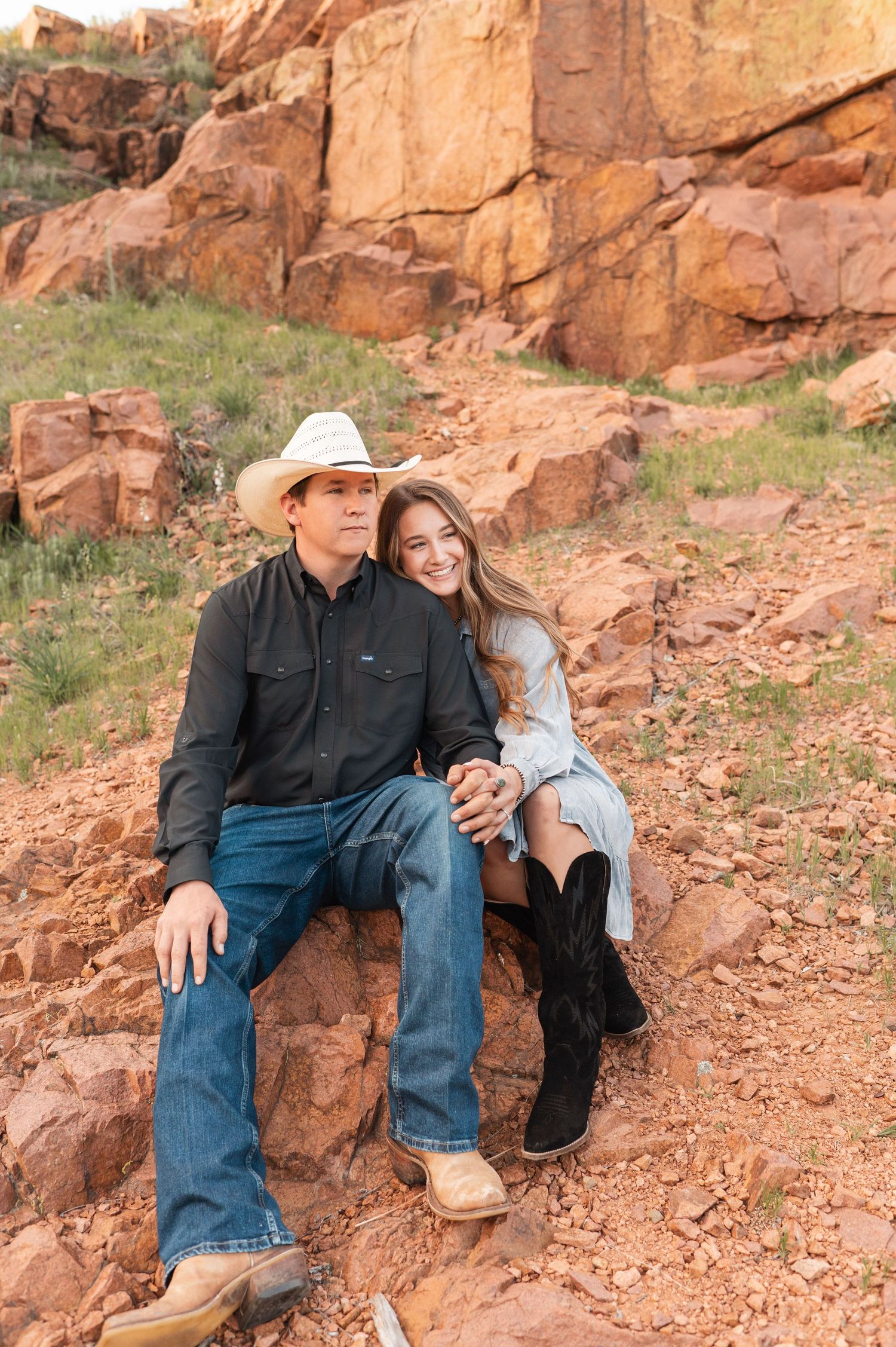 A couple sitting on desert rocks looking out into the distance.