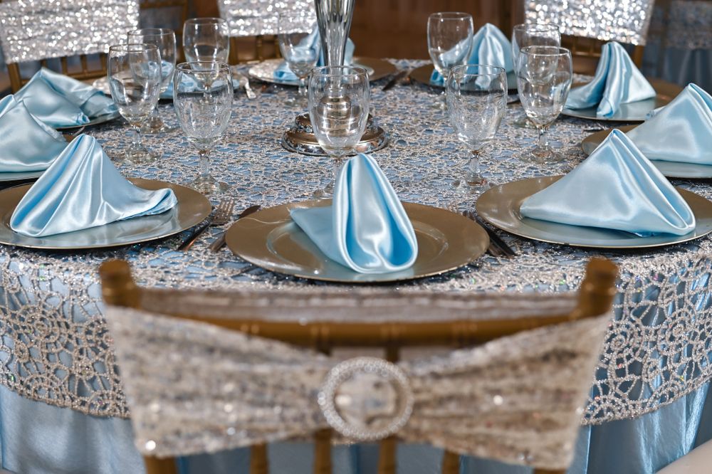 Elegant table setting with light blue napkins and silver sequin tablecloth at a formal event.