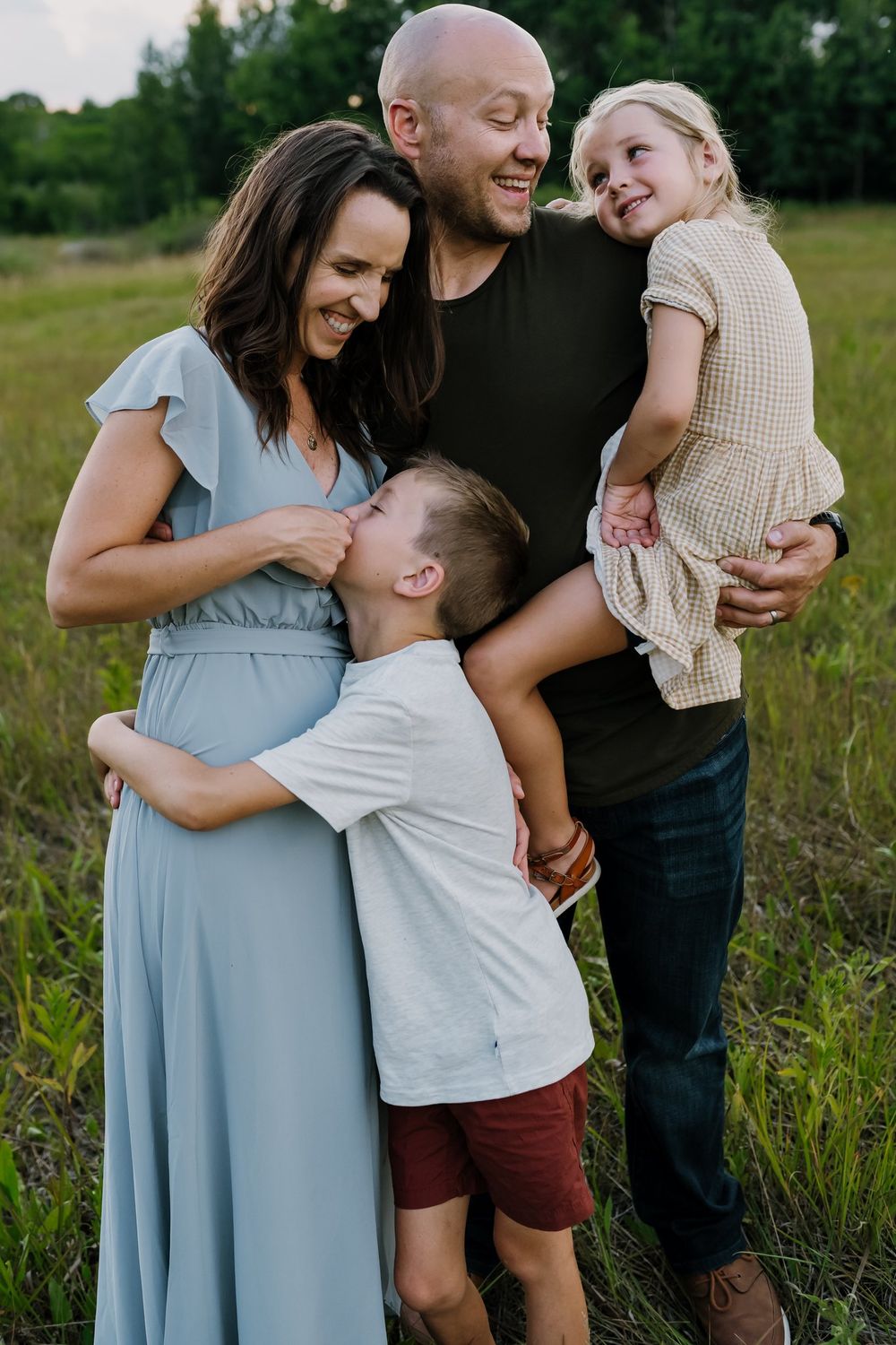 Family laughs together while standing in a field