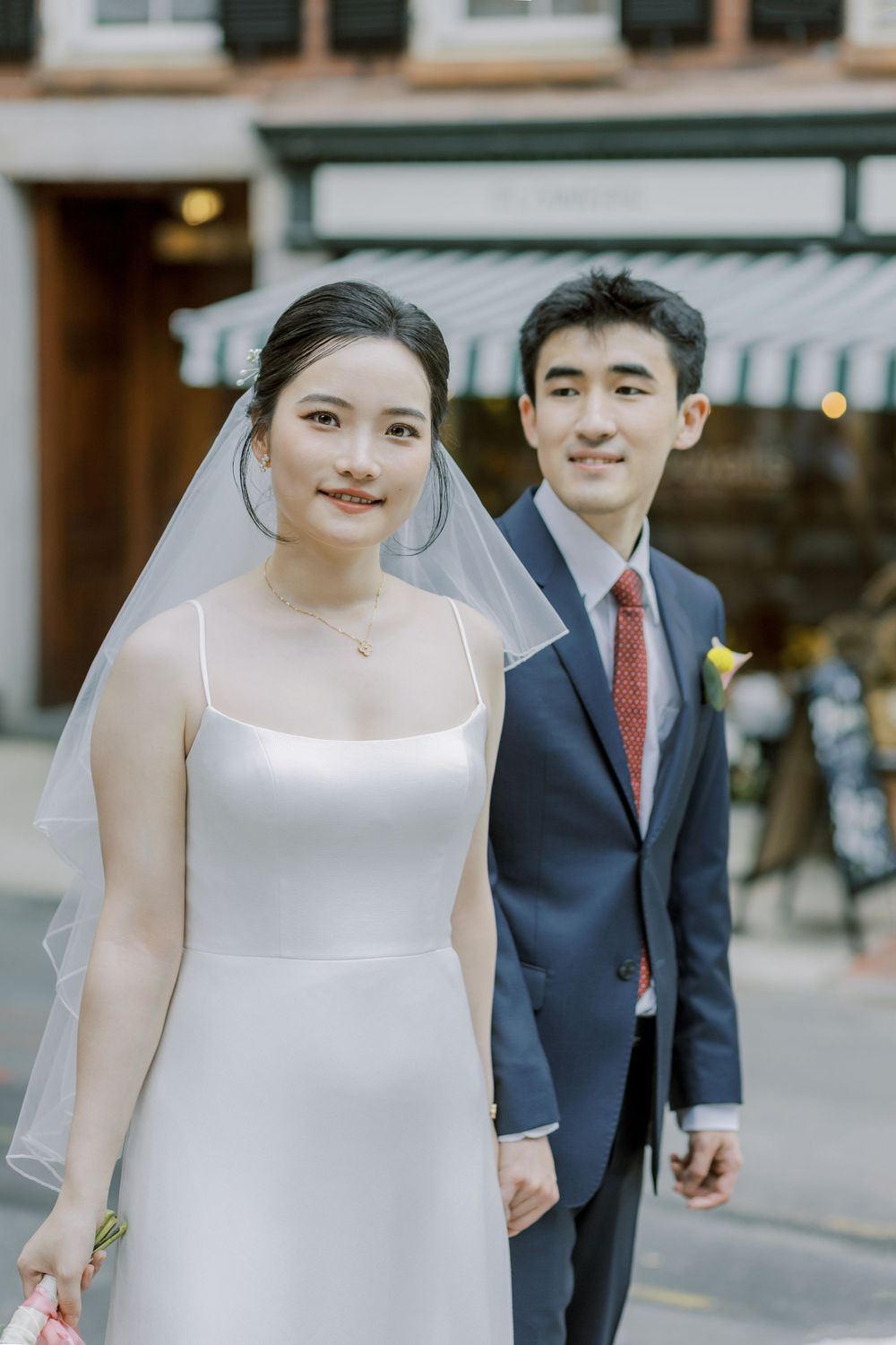 Elegant wedding portrait in front of a storefront with classic bridal attire.