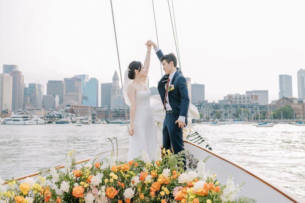 Wedding couple standing on a yacht with downtown skyline and colorful floral decorations.