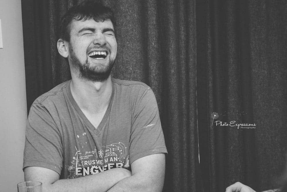A smiling person wearing a gray t-shirt in a casual indoor setting.