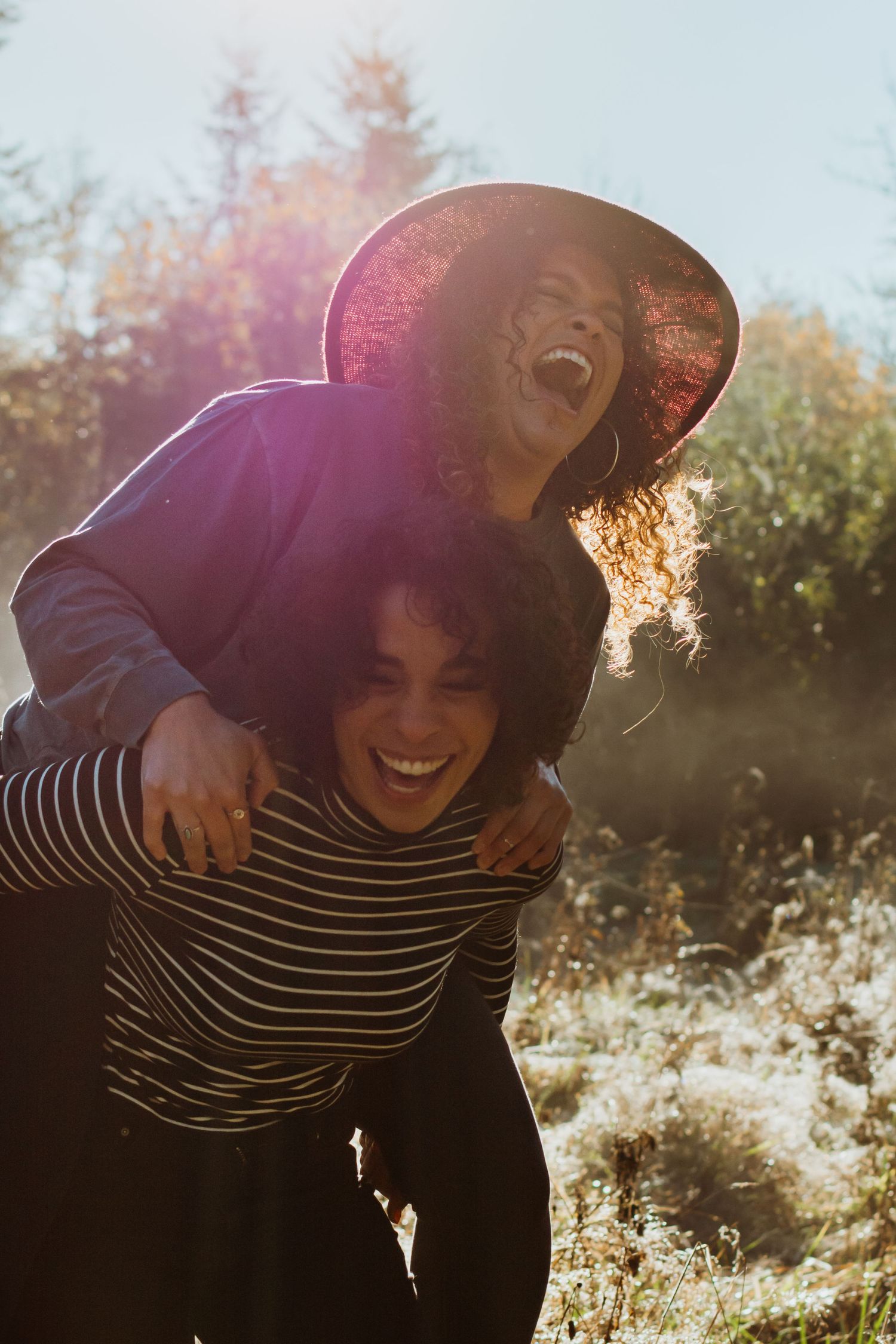 Joyful embrace captured in golden sunlight with lens flare effect.