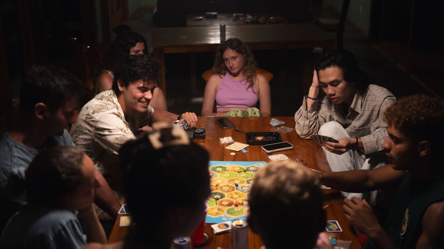 Friends enjoying a lively board game night with drinks and snacks.