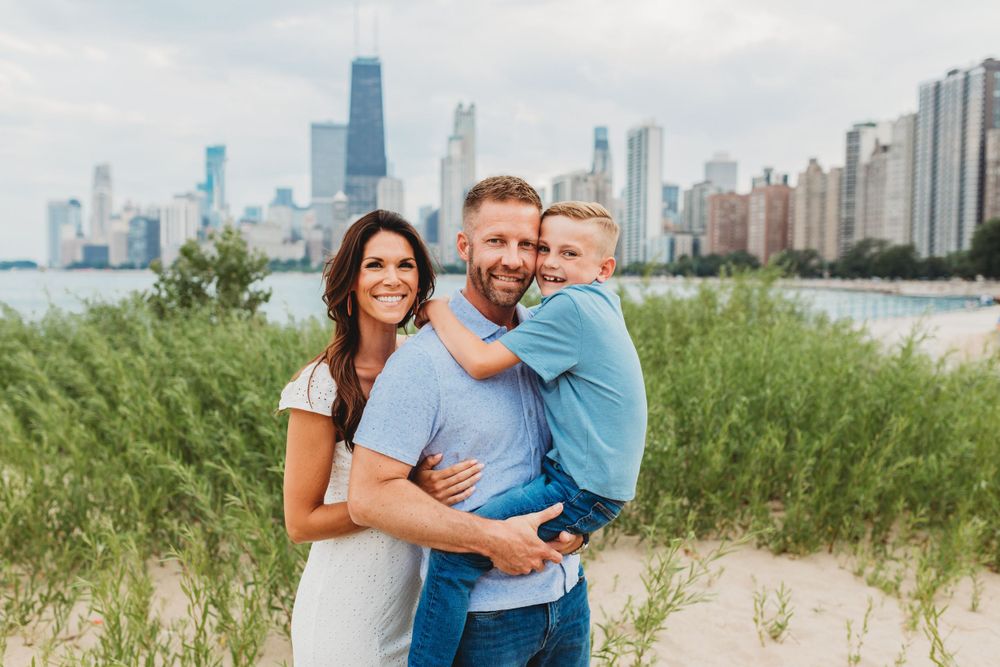 Family enjoys summer day at North Avenue Beach with Chicago cityscape visible.