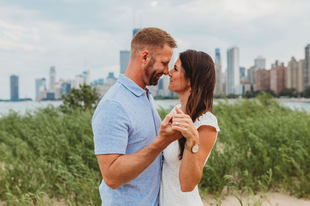 Couple laughs together during beach photoshoot with city views.