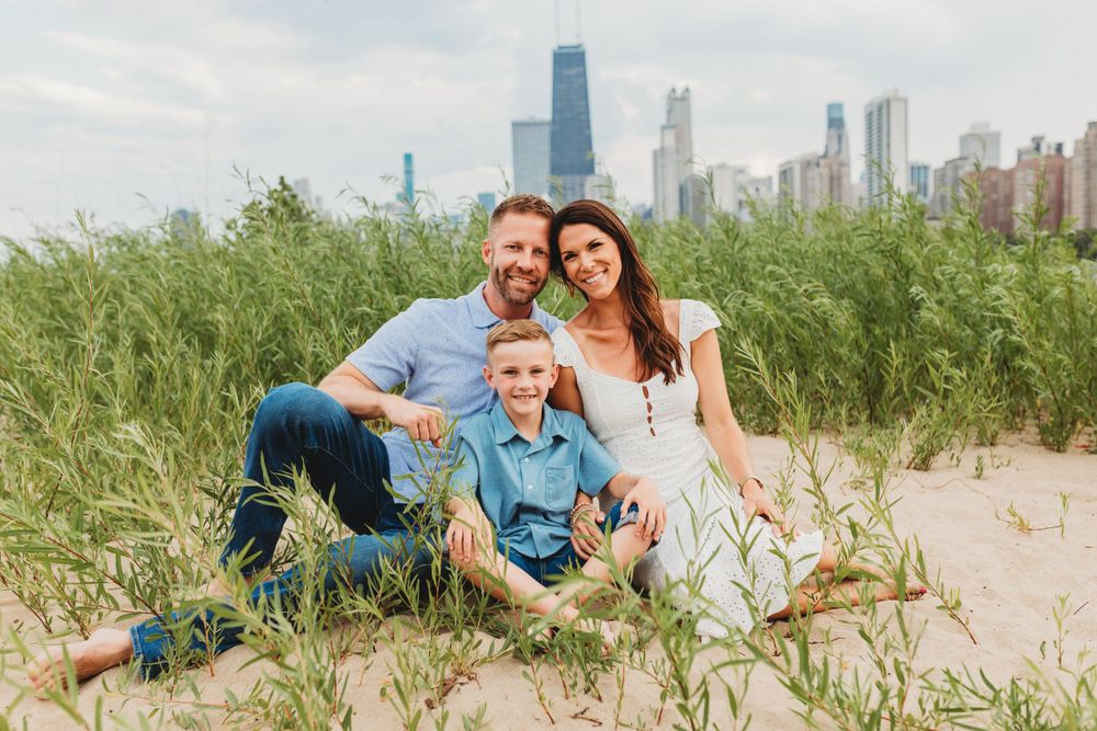 Family photo session on a sandy beach with Chicago skyline in background during golden hour.