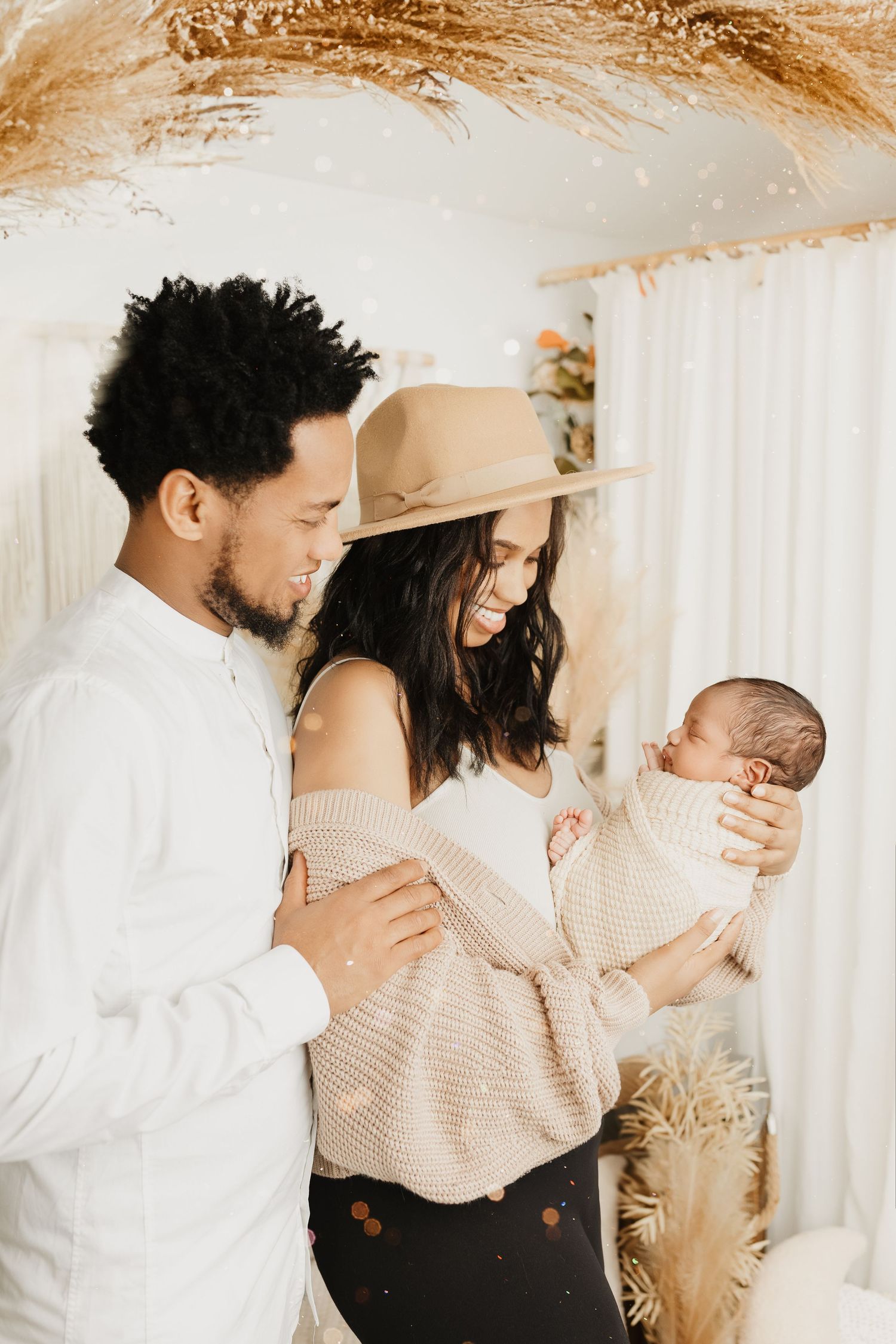 Candid family moments captured against neutral backdrop with dried pampas grass decor.