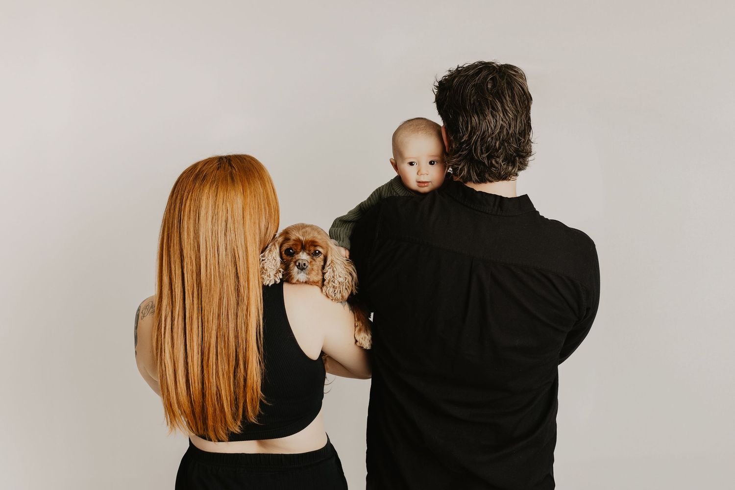 Candid family portrait series against white wall showing natural interactions.
