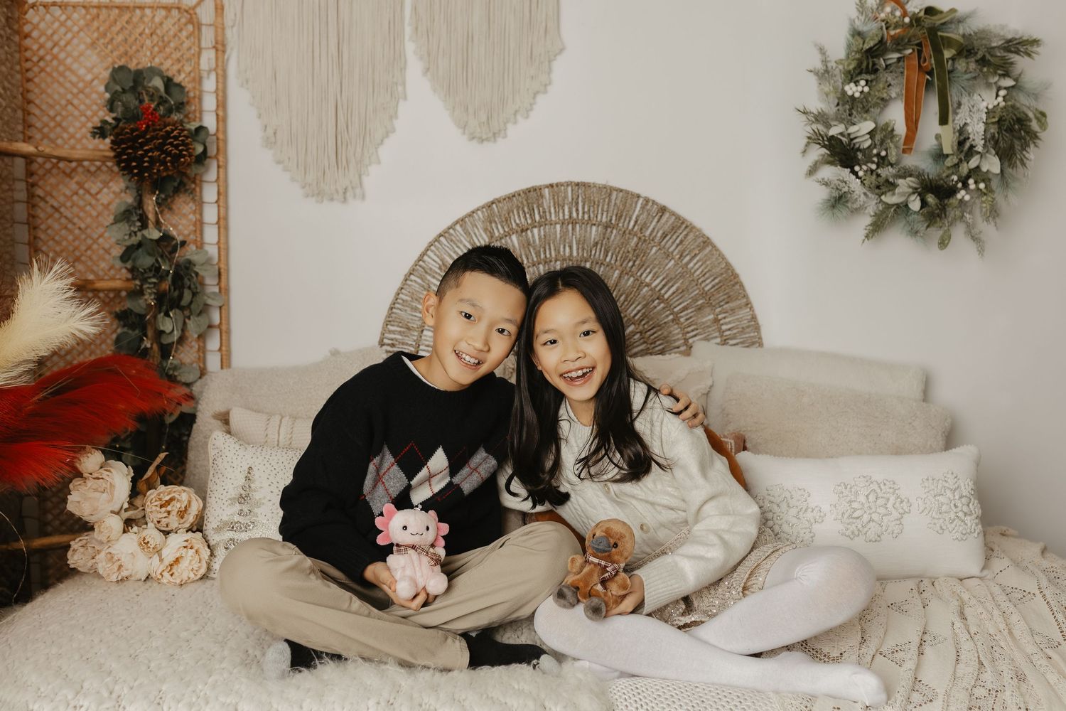 Holiday themed family photoshoot with festive decorations and cozy white bedding.
