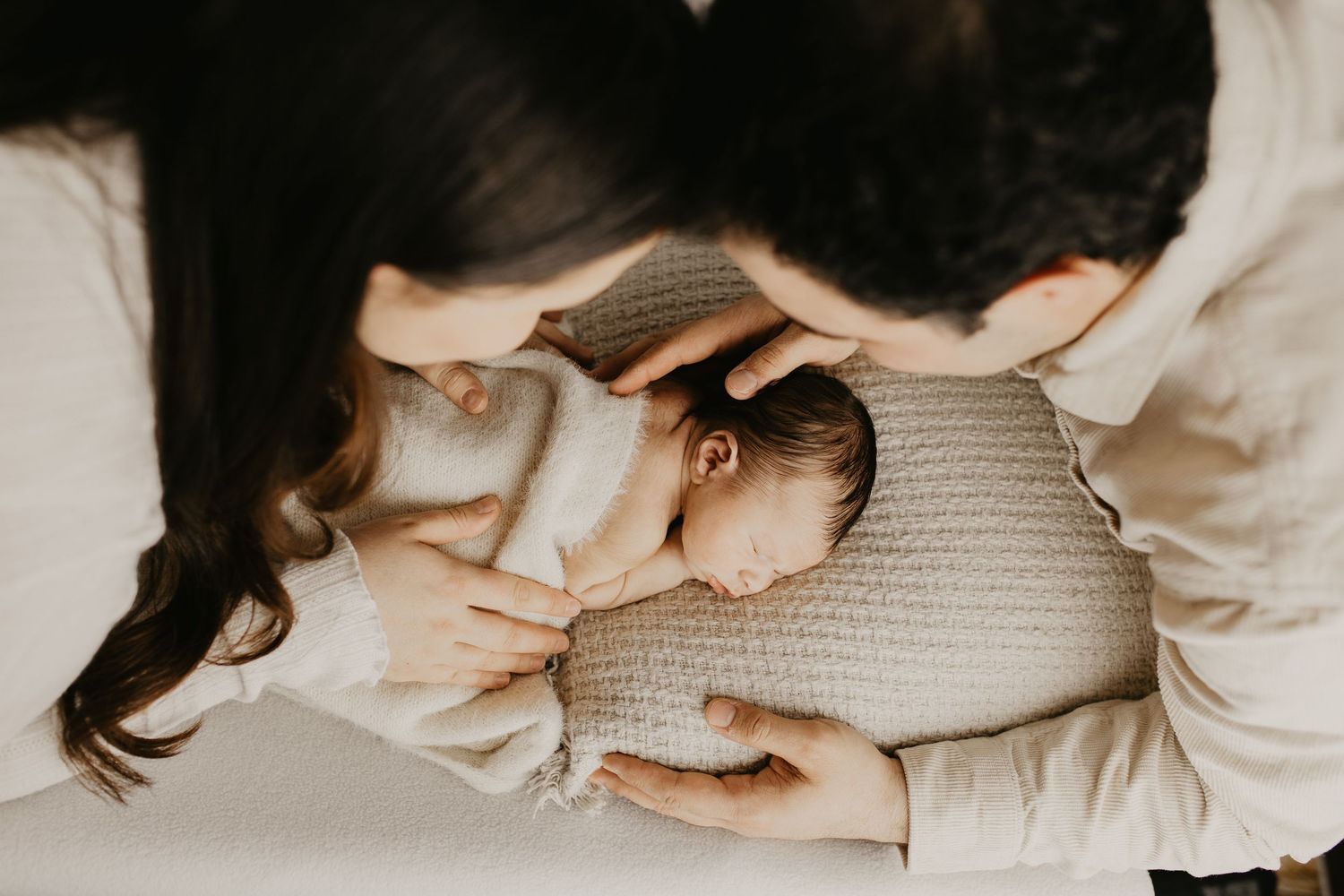 Intimate family photo session showing tender moments between parents and baby on light backdrop with pampas grass decor.