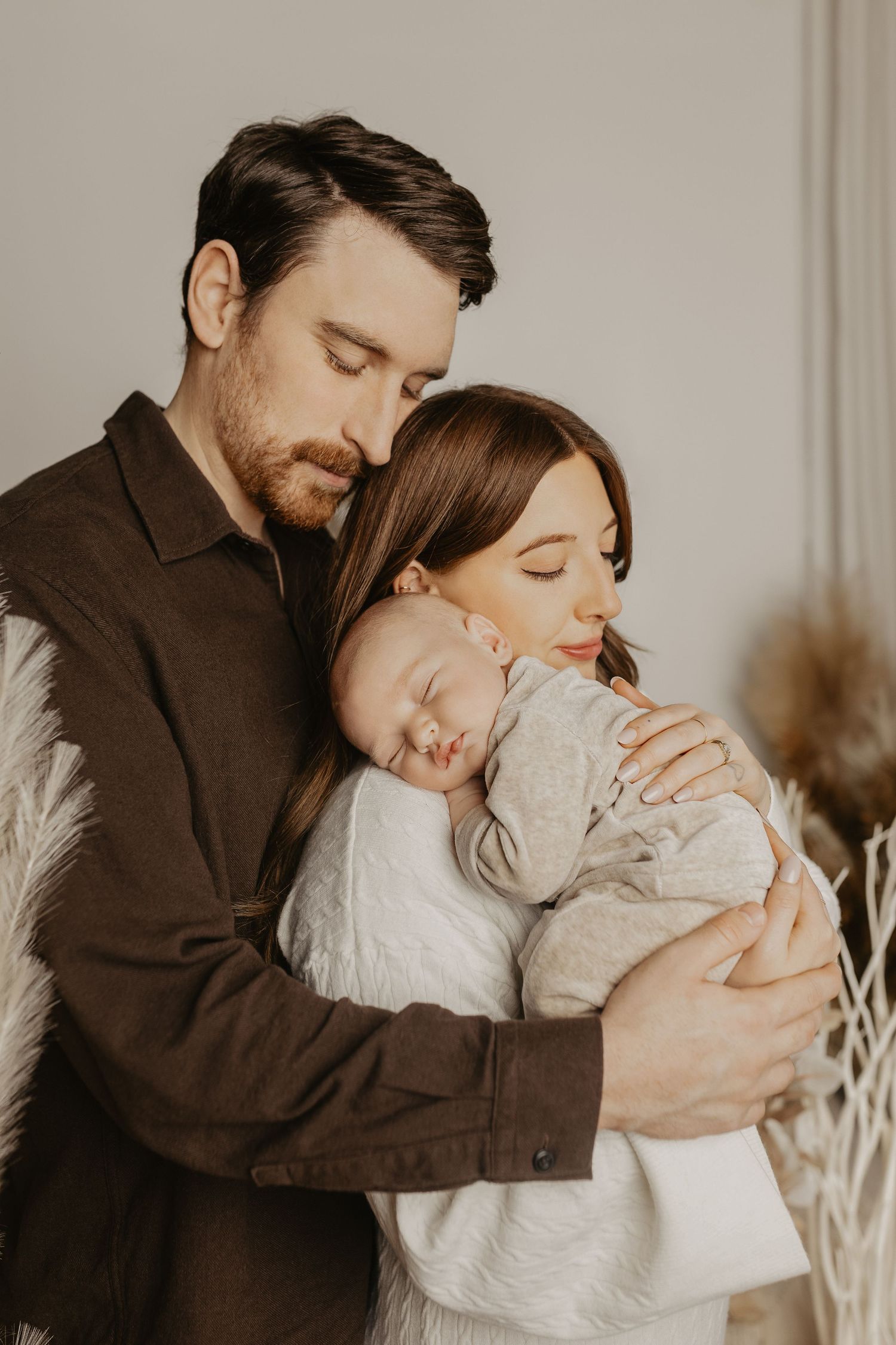 Family sharing intimate moments with newborn baby in cozy studio setting.