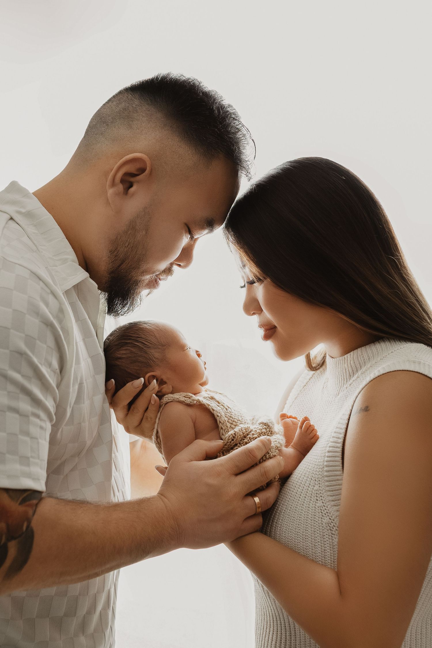 Intimate black and white photo series showing tender moments between parents and their newborn baby.
