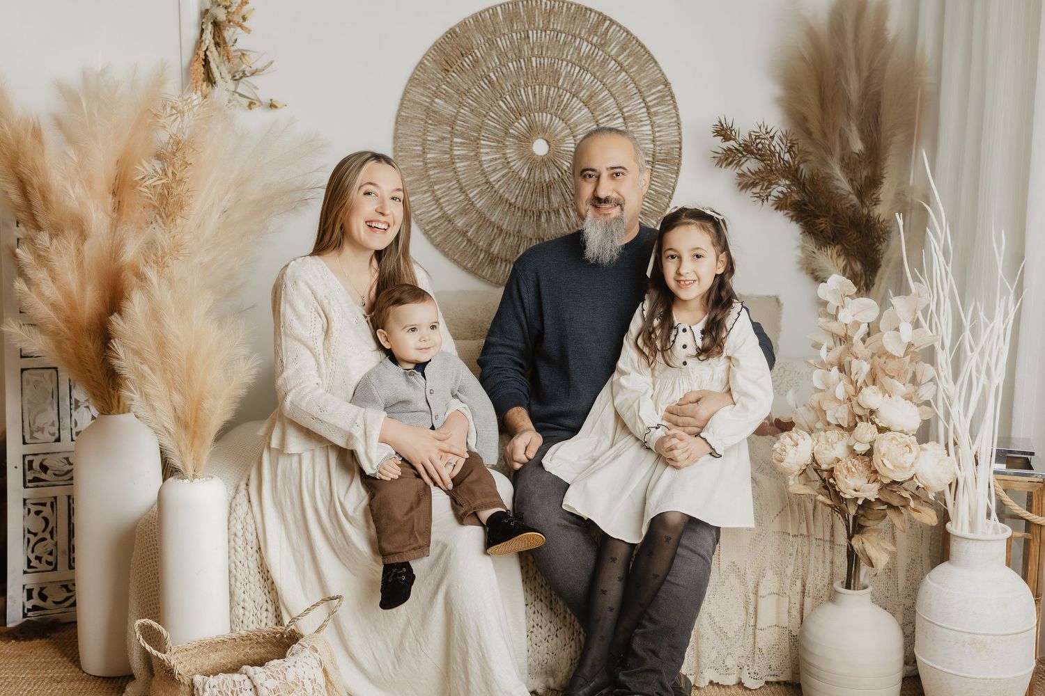 Modern family photoshoot in cream colored studio with boho decorative elements.