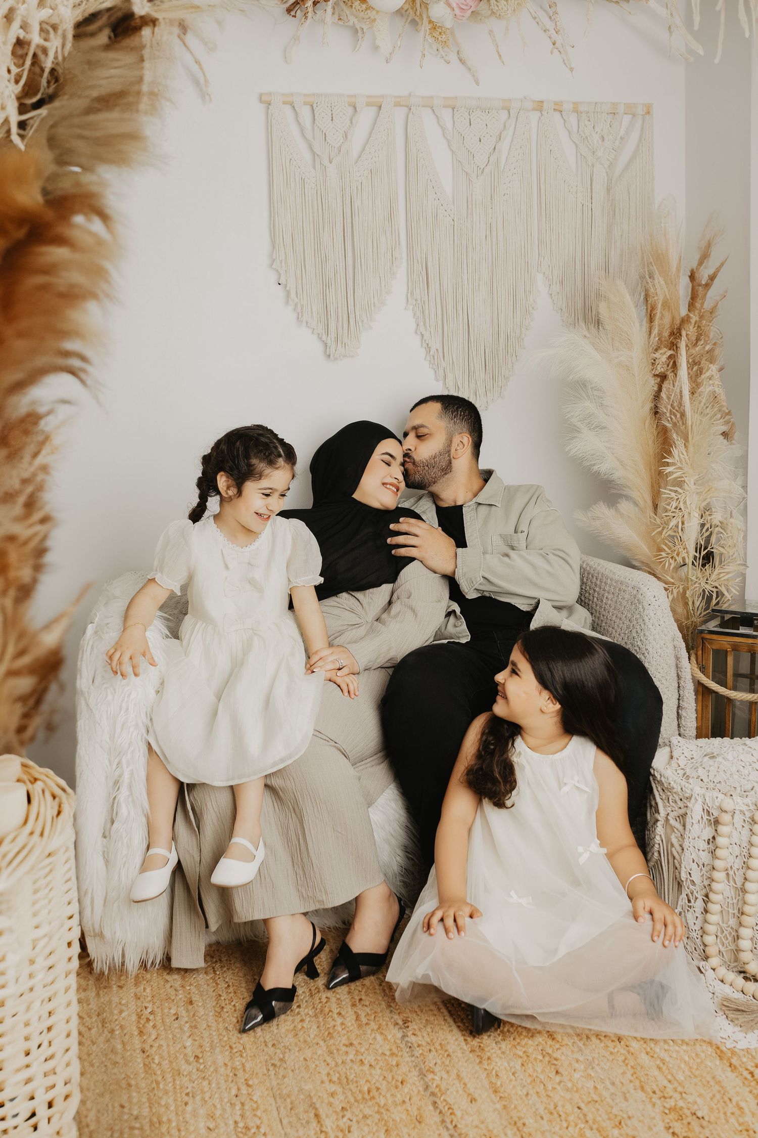 Candid family moments captured on white couch with boho-inspired neutral decor.