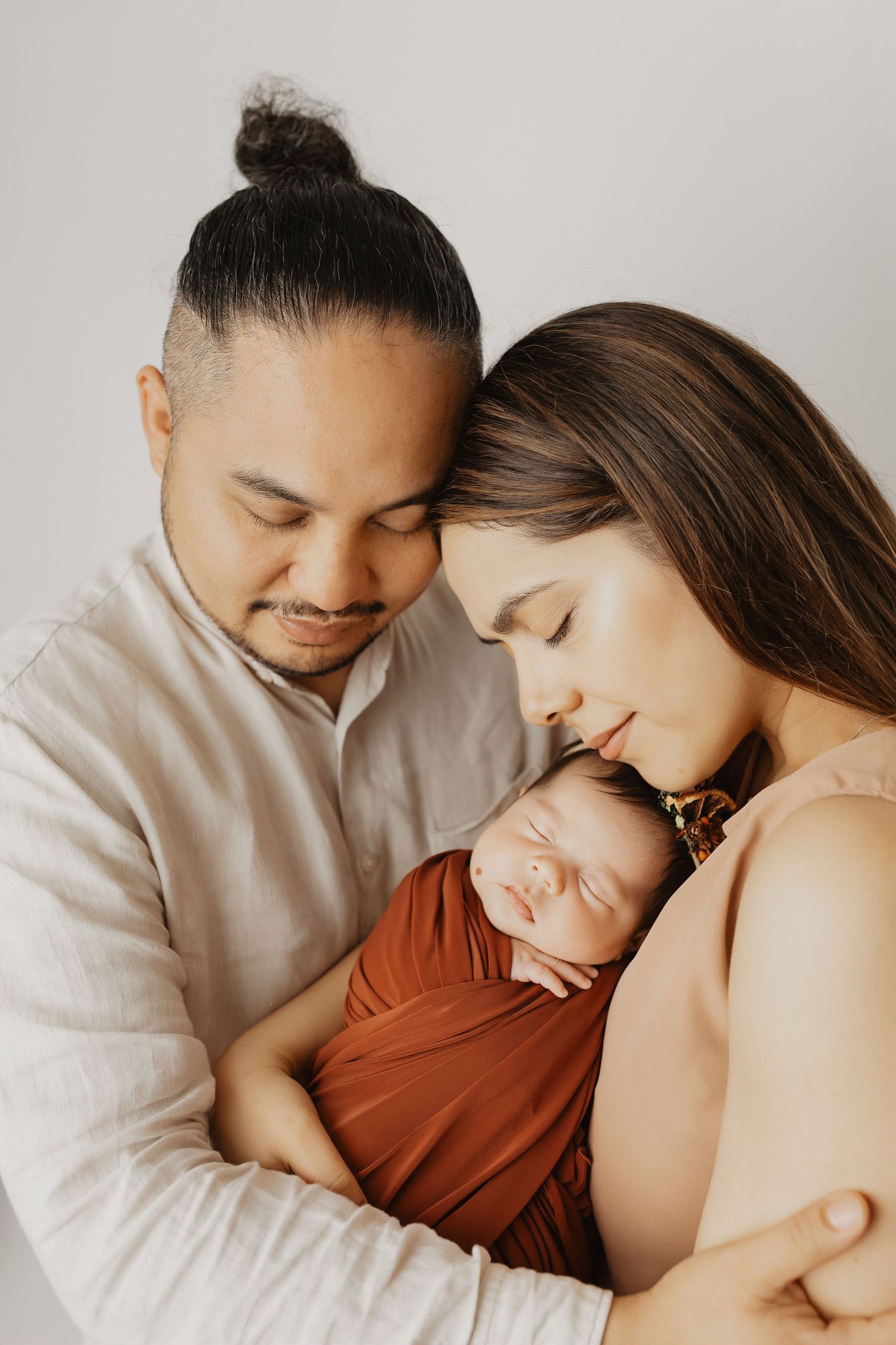 Minimalist studio family portrait session capturing tender moments with newborn.