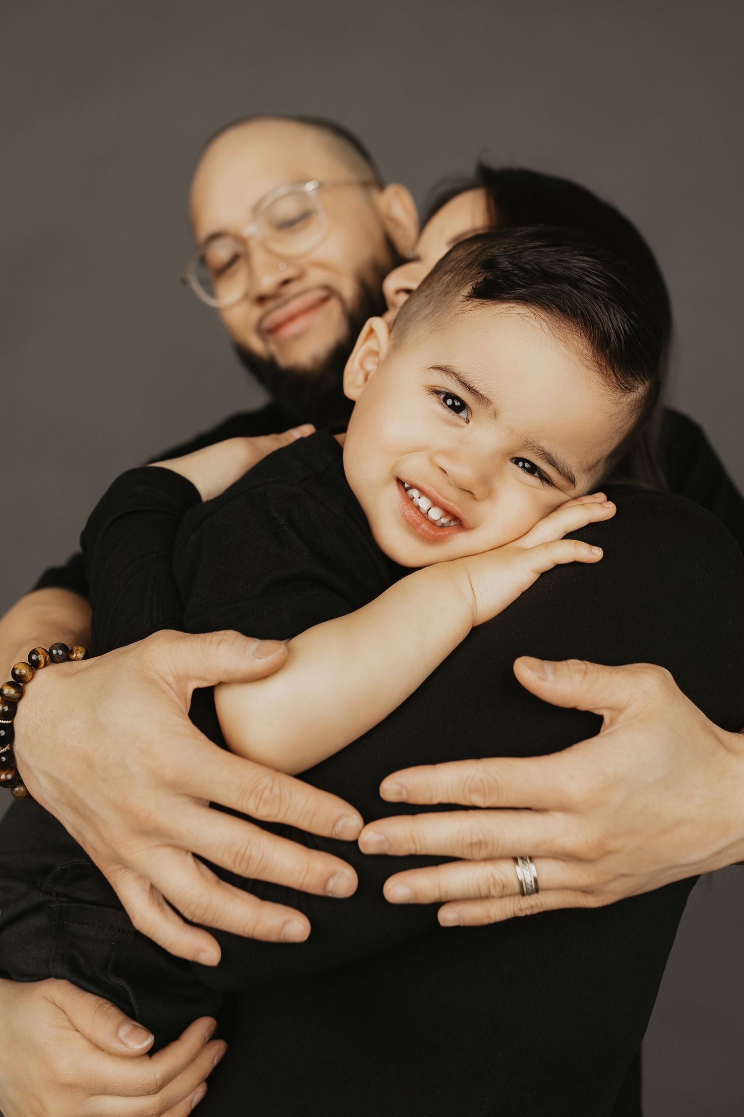 Father tenderly embracing smiling toddler son in a warm studio portrait.