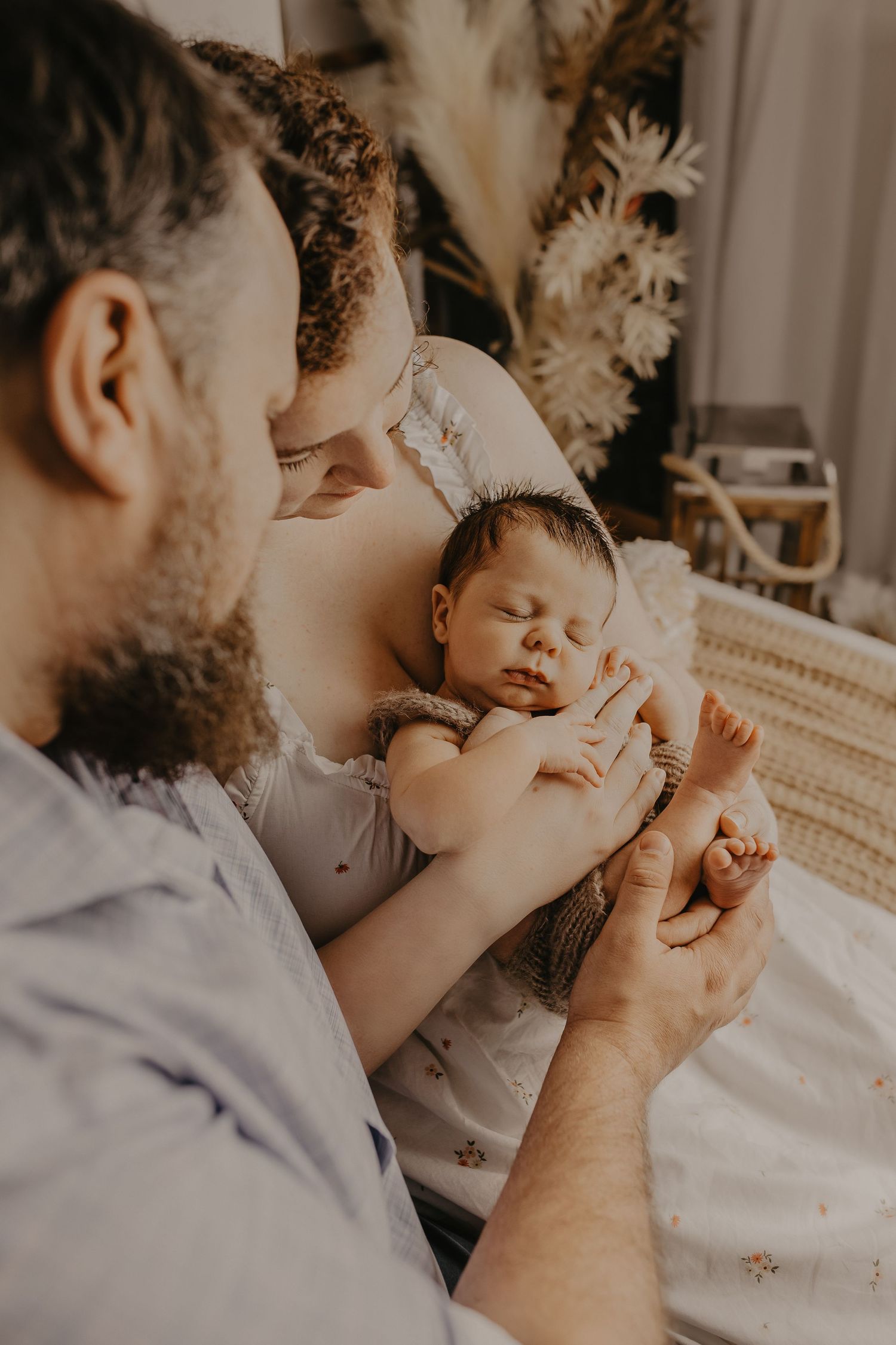 Intimate close-up shots of parents kissing their newborn's tiny hands in soft natural light.