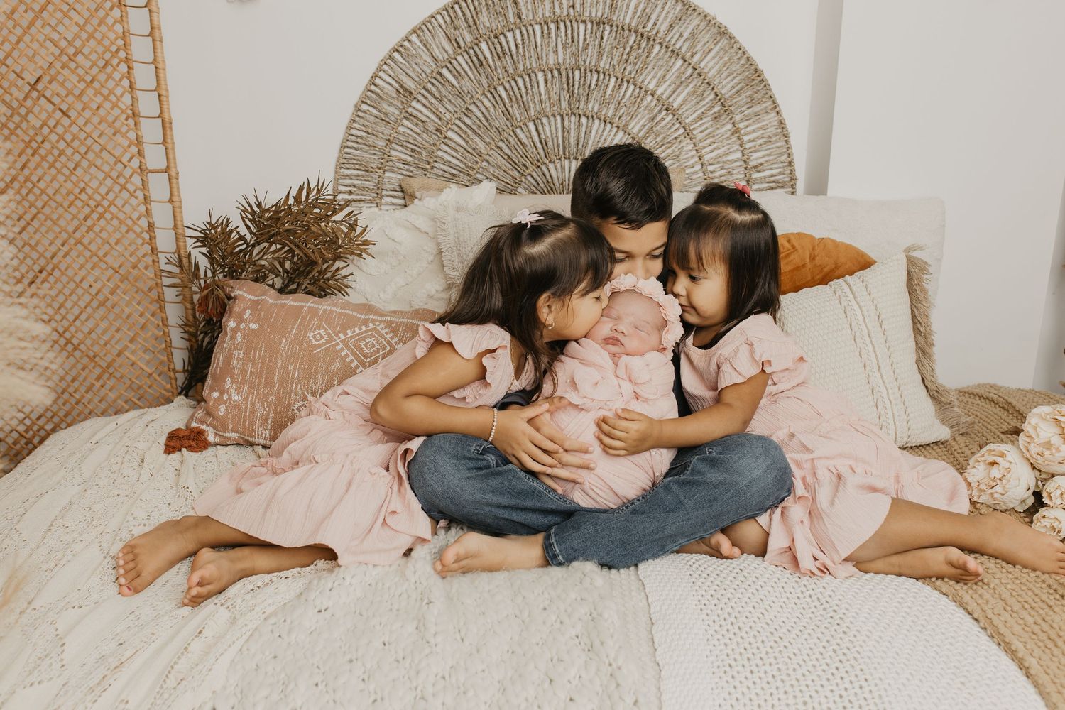 Intimate family lifestyle photography session on white bedding with neutral tones.