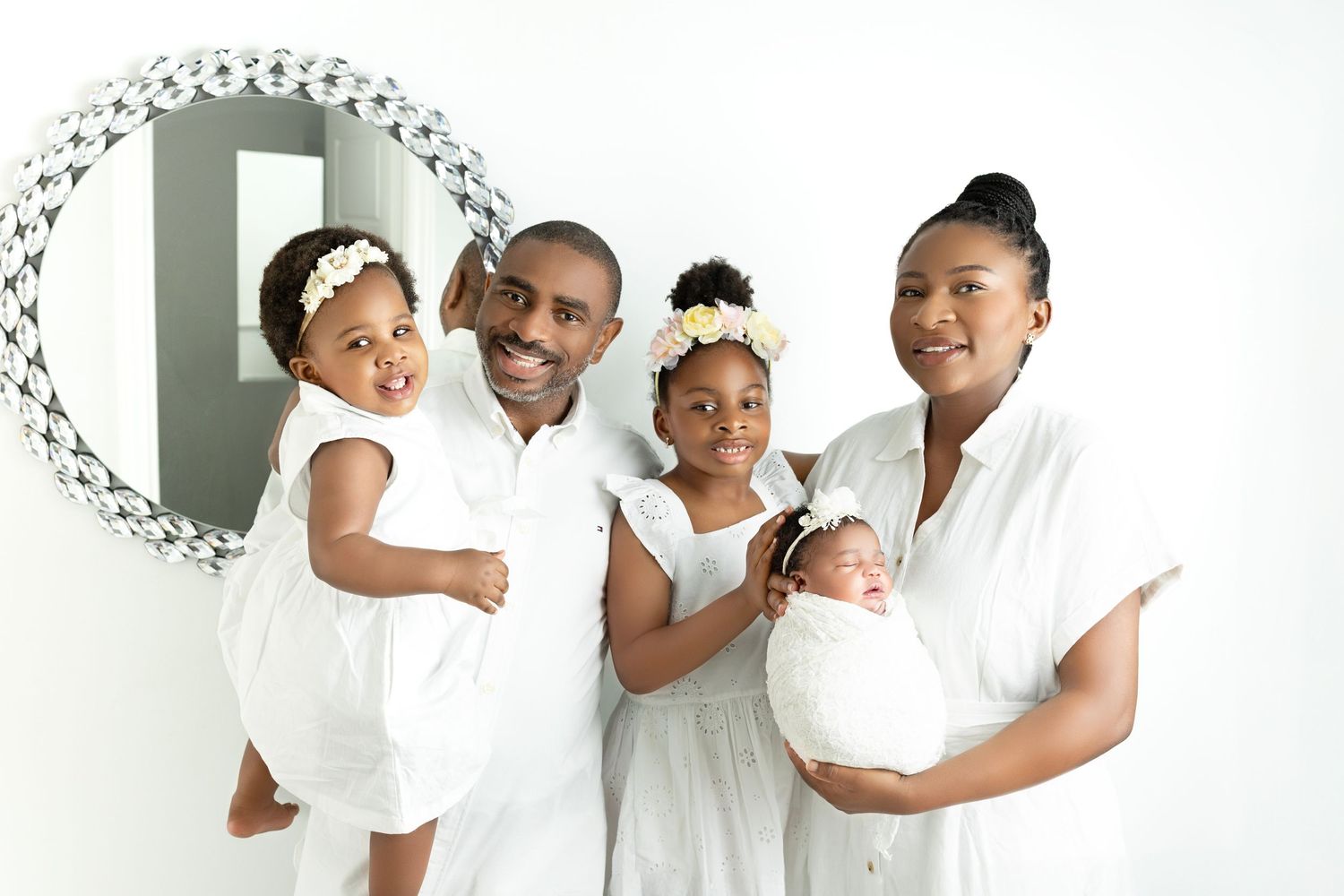 Modern family portrait session in white studio setting with coordinated outfits.
