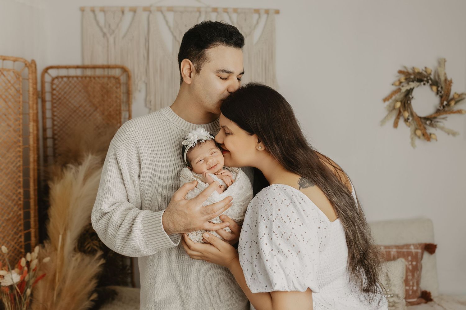 A cozy indoor family portrait with boho decor and warm neutral tones.