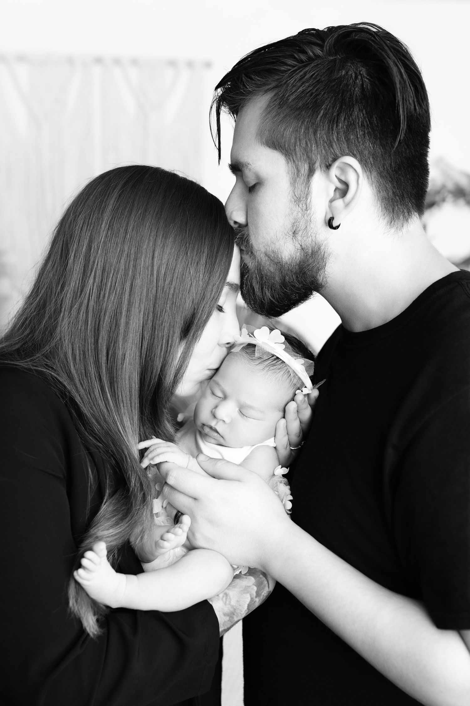 Black and white photo series capturing tender moments between parents and their baby.