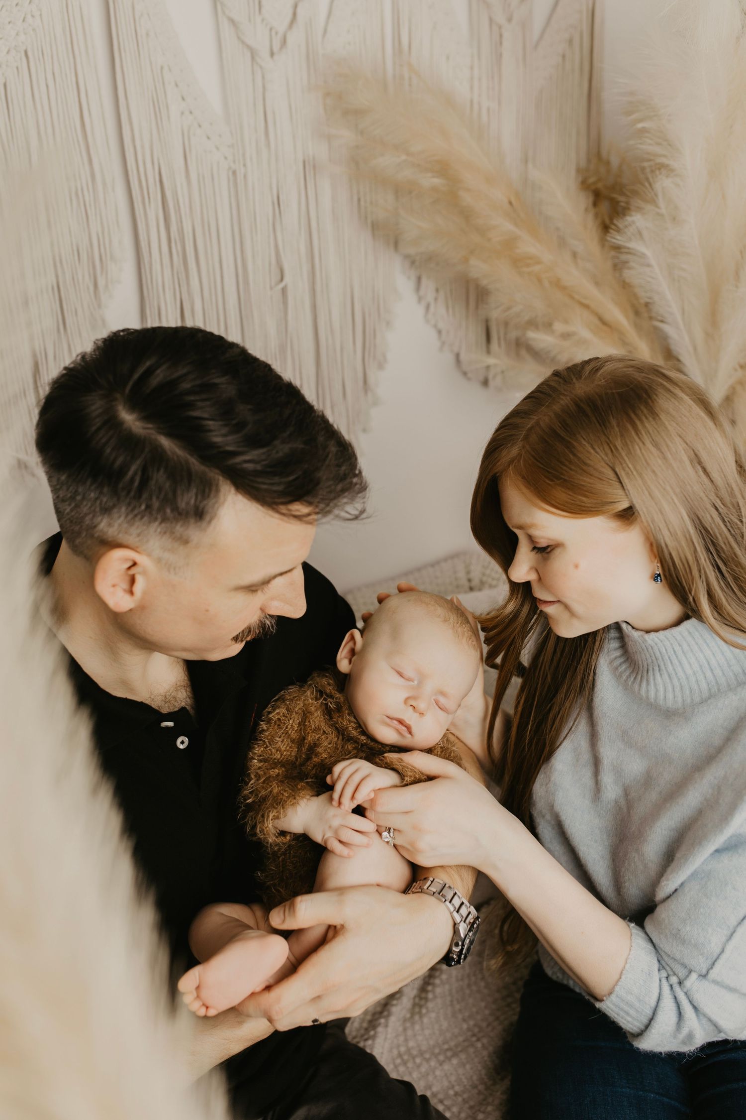 Sweet family bonding moment captured in soft neutral tones with decorative macrame wall hanging.