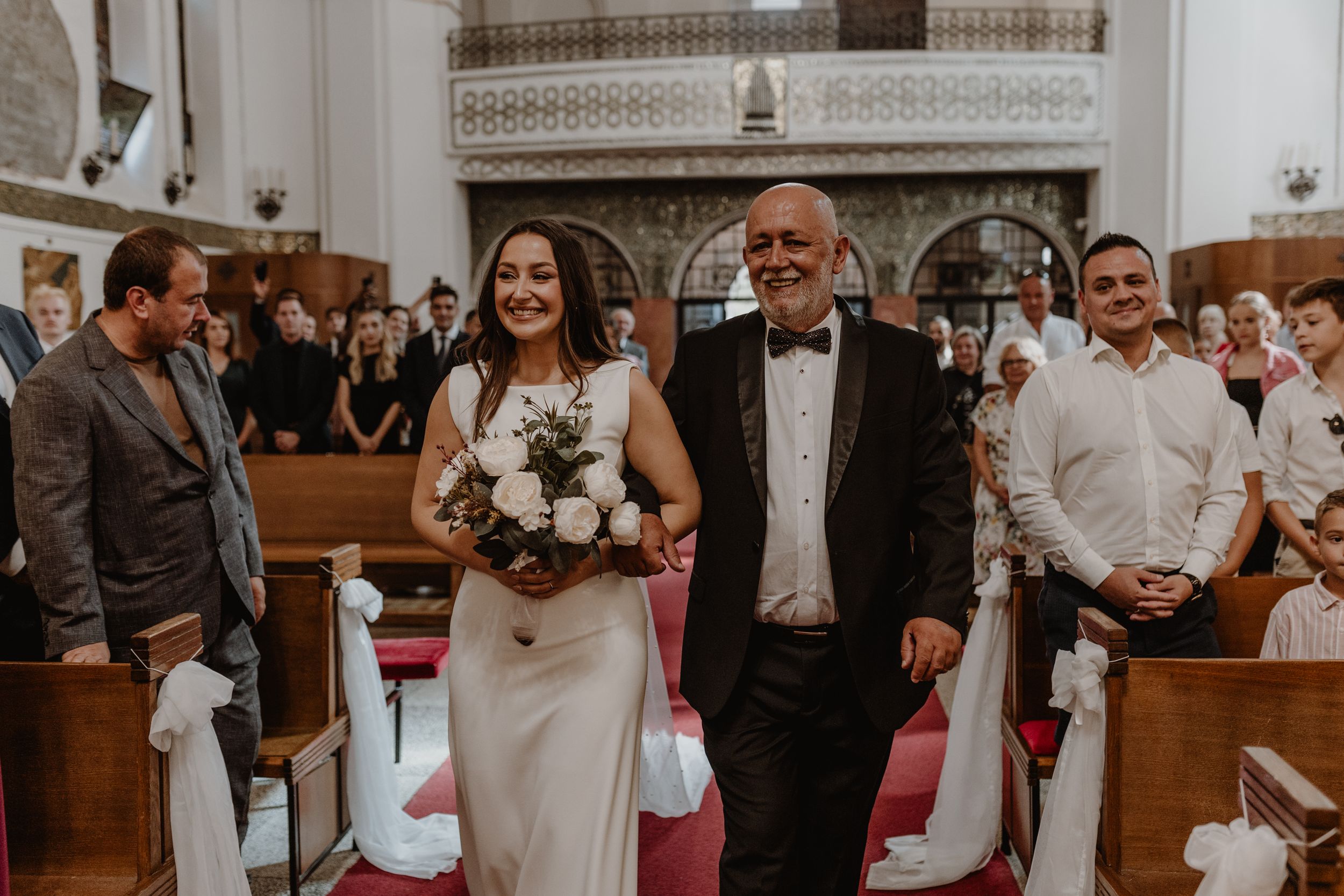 Mladenka i njen otac hodaju prema oltaru u crkvi sv. Petra u Zagrebu prikazano kroz vjenčanu fotografiju.