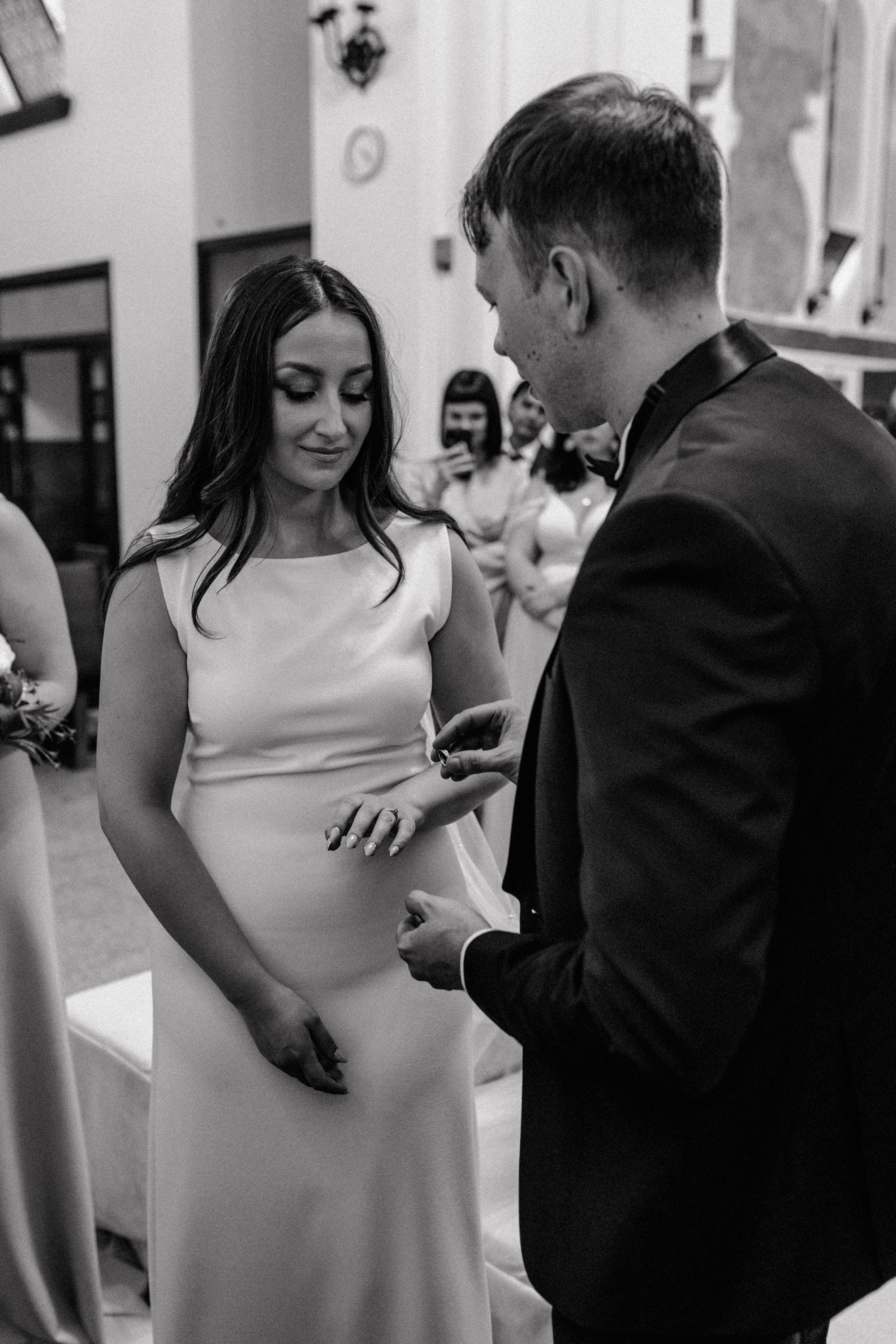 Black and white wedding photograph of exchanging rings during wedding ceremony in st Petar church in Zagreb.