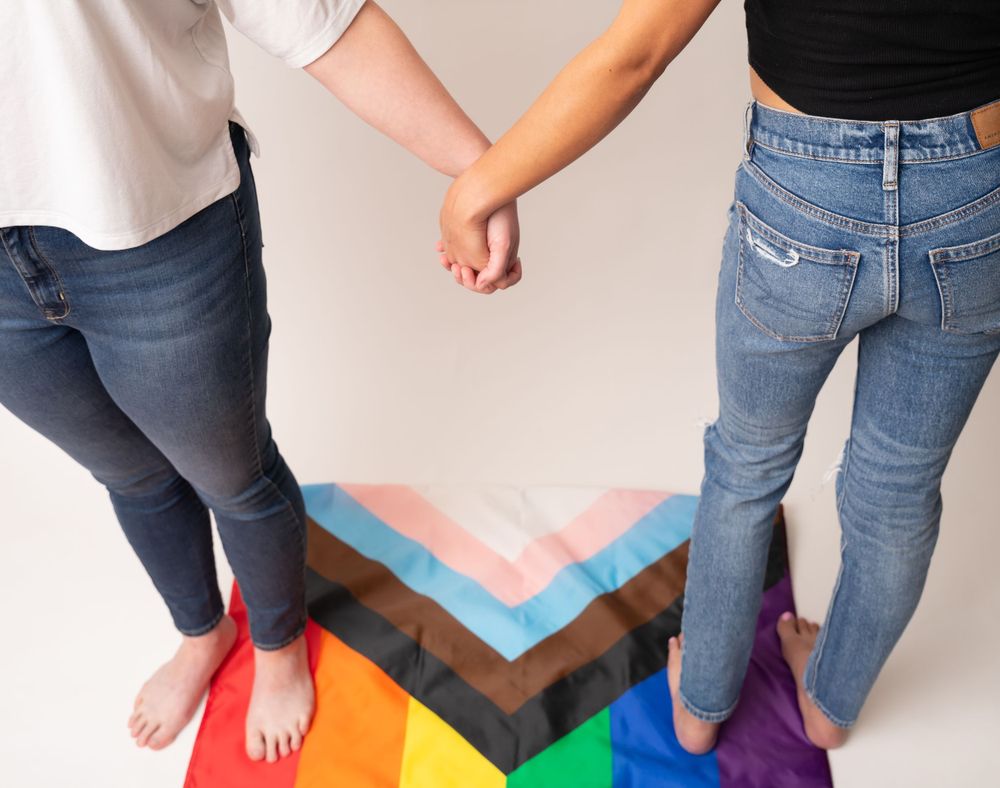 Close-up of feet and legs on colorful rainbow floor pattern.