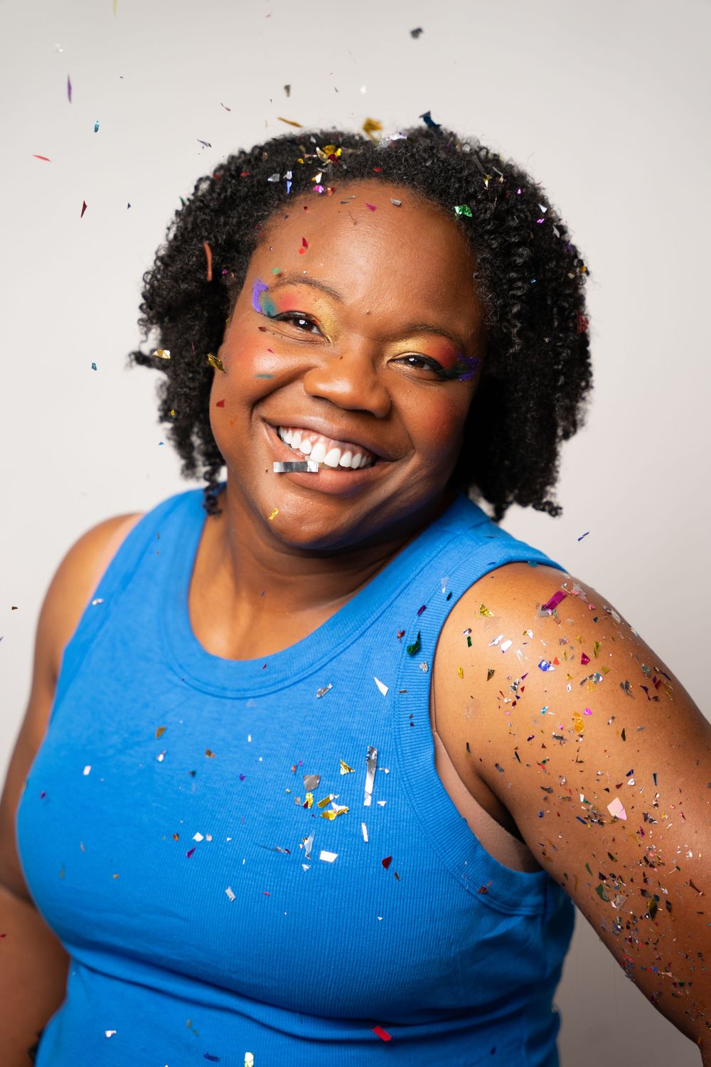 Joyful confetti celebration portraits with bright blue tank top against white backdrop.