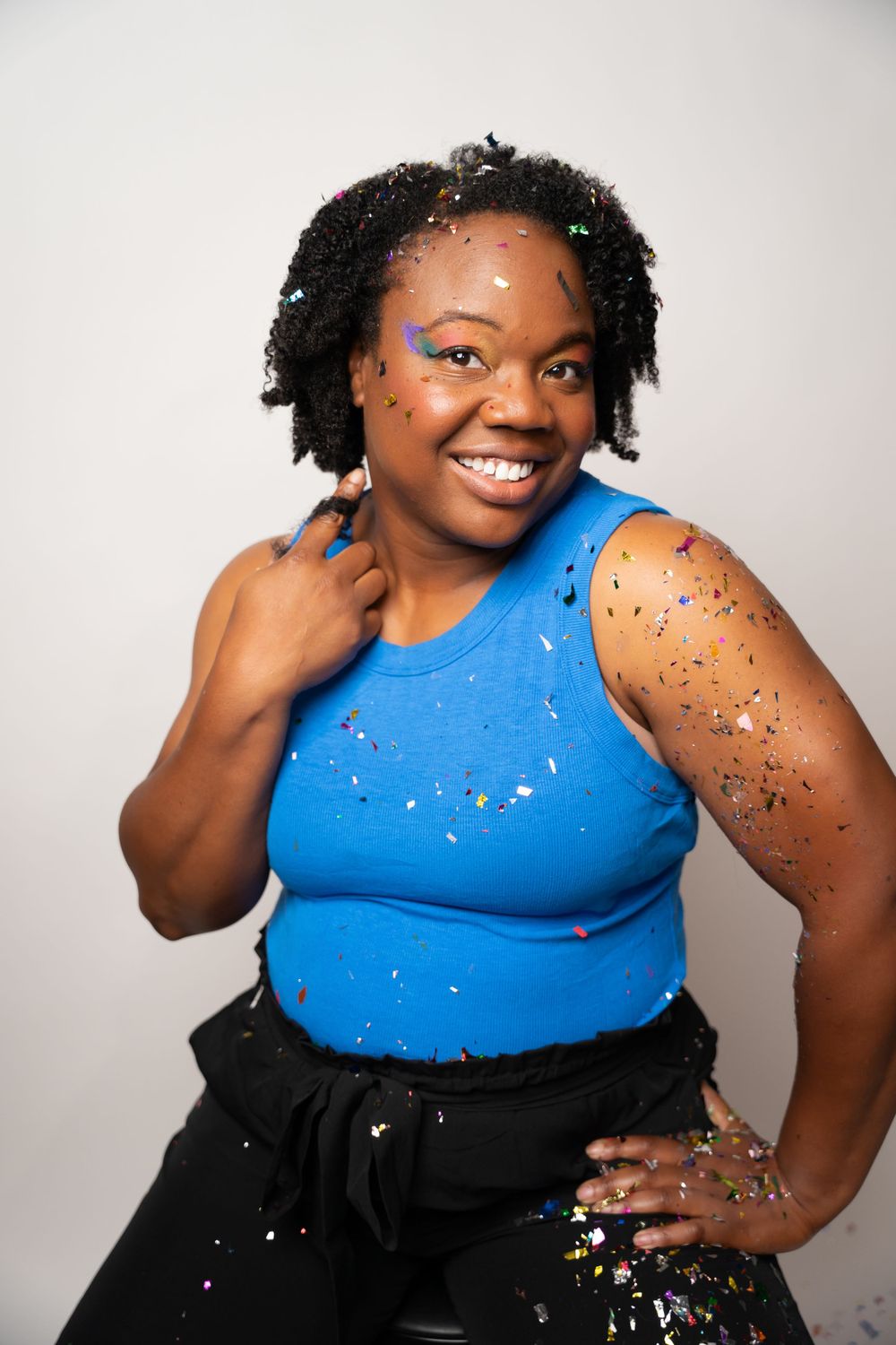 Festive photoshoot featuring a bright blue top and black skirt with glitter accents.