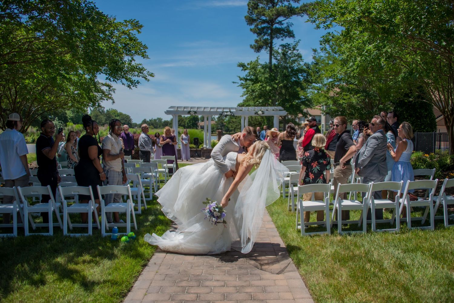 Groom dipping bride for kiss with guests behind