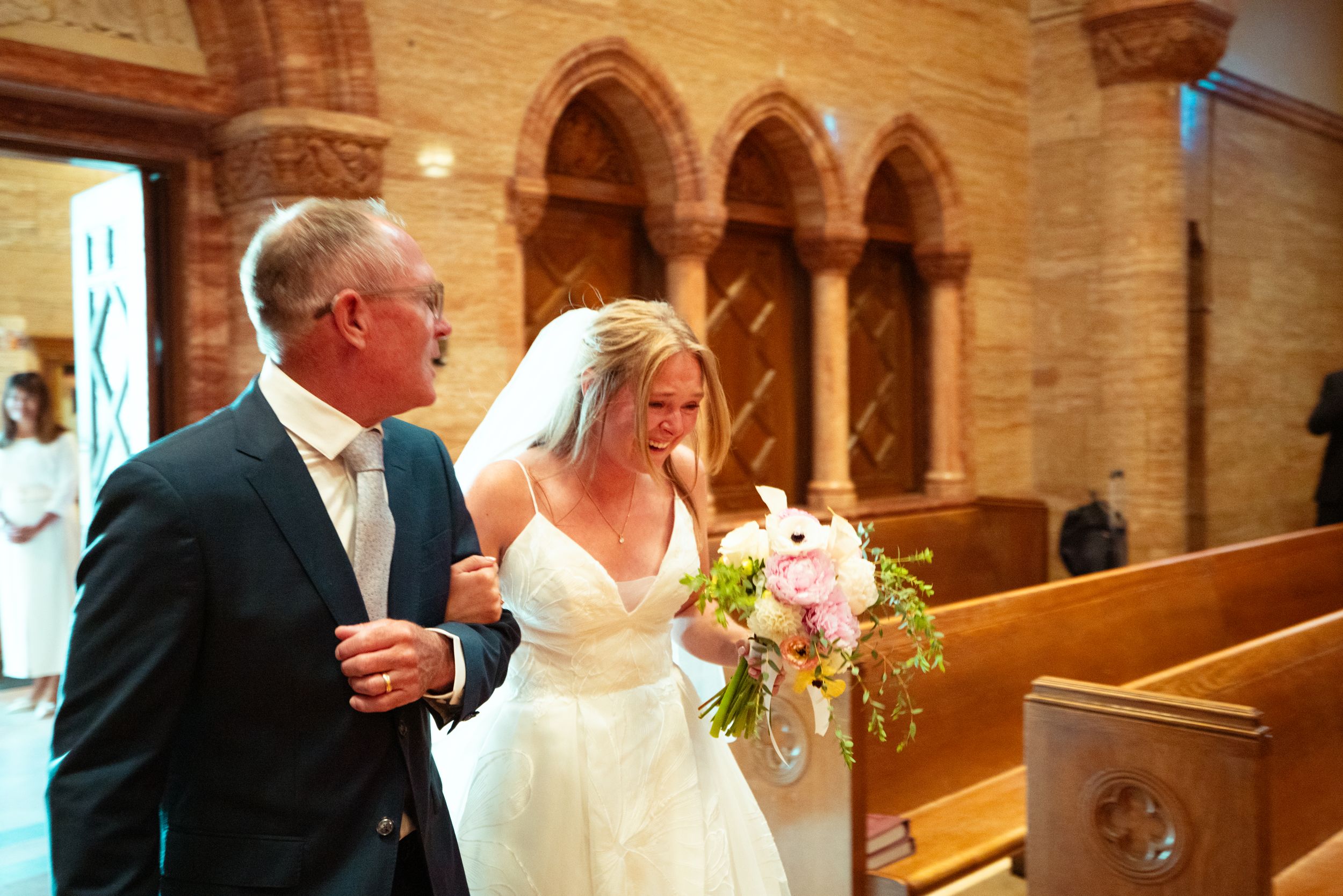 Wedding ceremony taking place inside a traditional church with gothic arches and wooden pews.